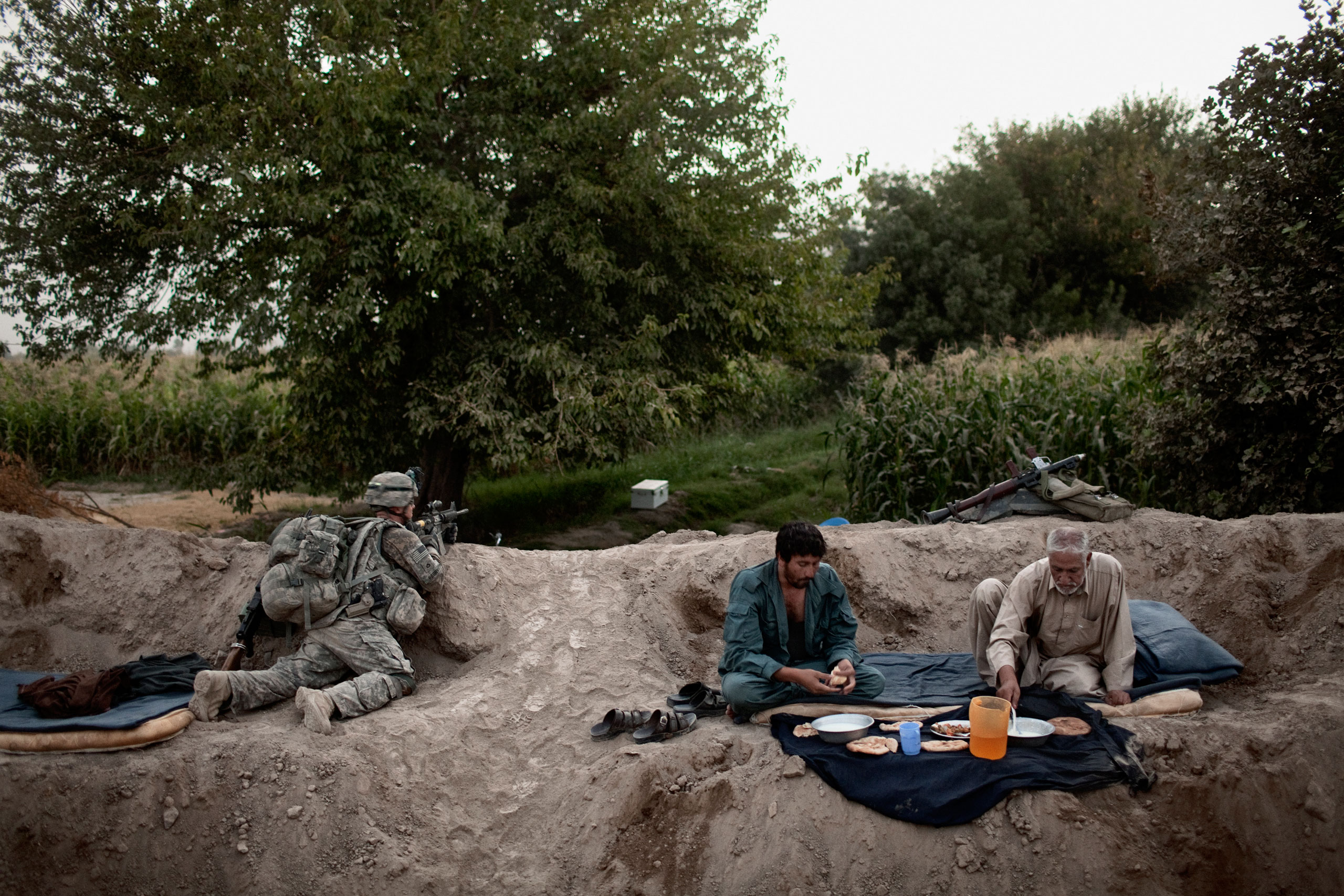 Afghan National Police broke their fast for Iftar during Ramadan while a soldier from the 504th U.S. Military Police Battalion provided security in the Mehlajat area of Kandahar City, Afghanistan, 2010.