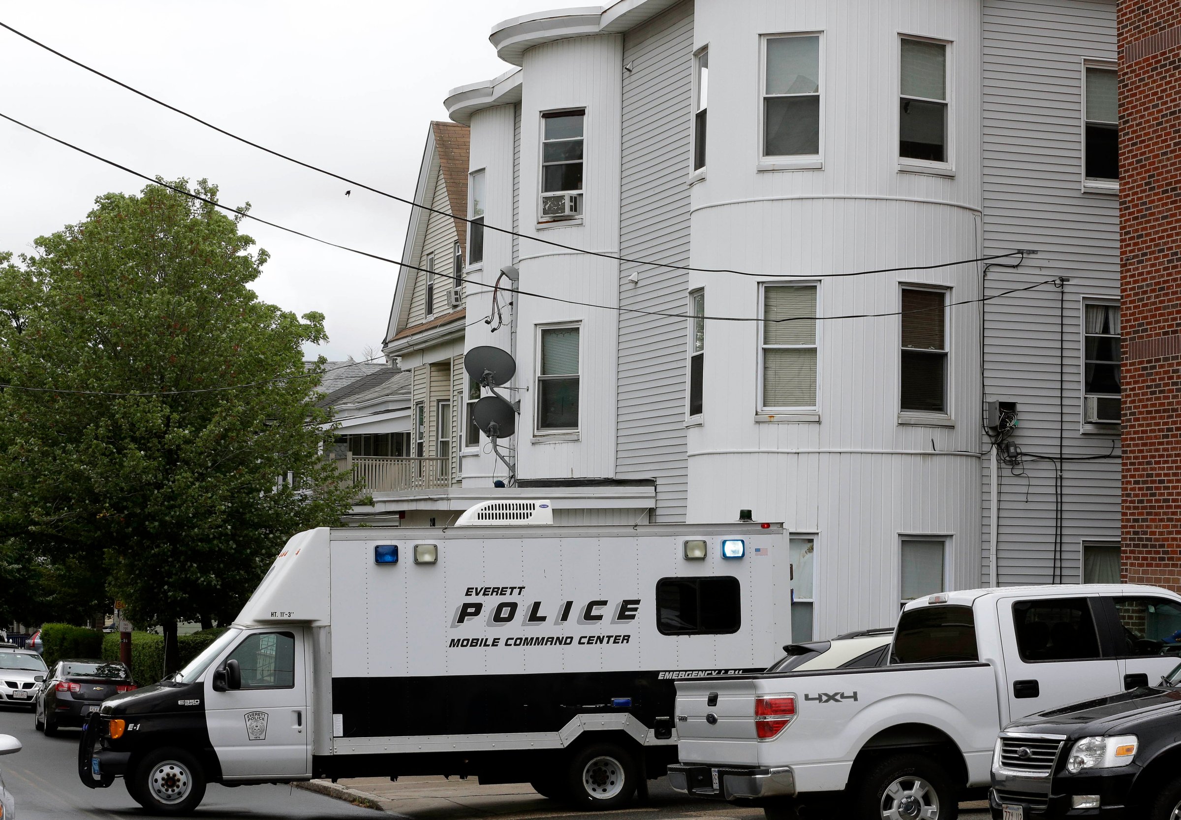 Police vehicles sit in front of a multi-storied home on June 2, 2015, in Everett, Mass., being searched by authorities in connection with a man shot and killed earlier in the day in Boston. The man, under surveillance by terrorism investigators, was killed after he lunged with a knife at a Boston police officer and an FBI agent.