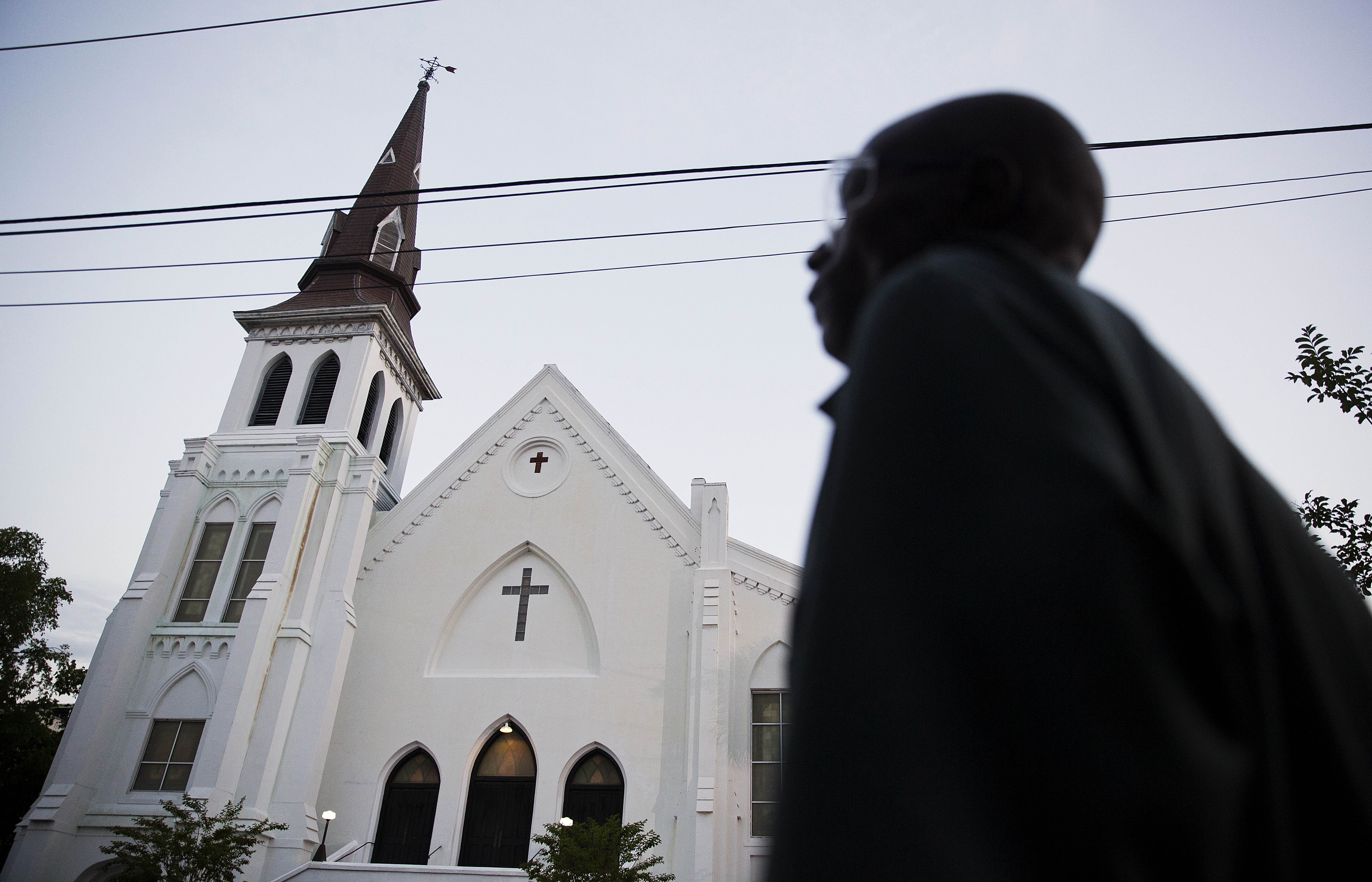 The steeple of Emanuel African Methodist Episcopal Church stands as a pedestrian passes early June 21, 2015, in Charleston, S.C. (David Goldman—AP)