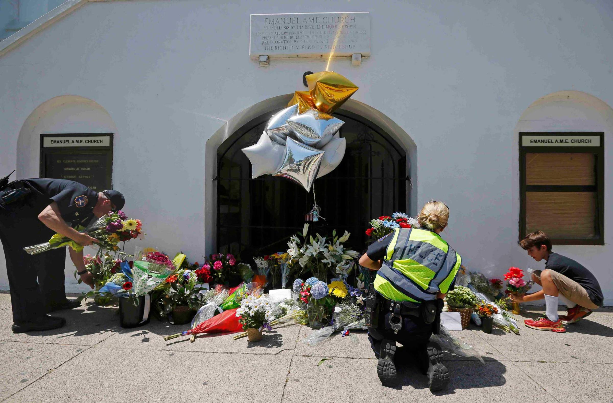 Nine-year-old Liam Eller helps police officers move flowers left behind outside Emanuel African Methodist Episcopal Church after the street was re-opened a day after a mass shooting left nine dead during a bible study at the church in Charleston