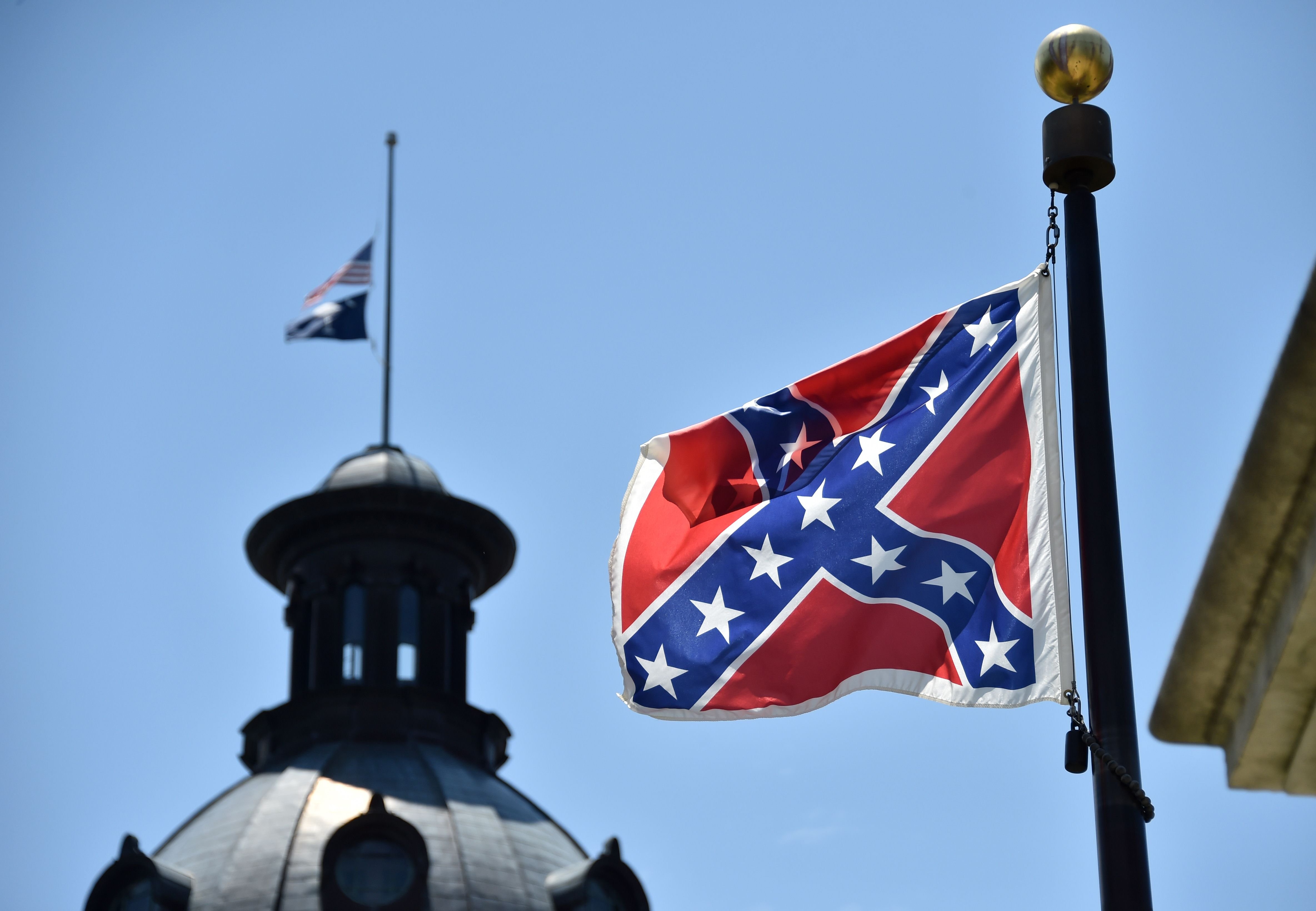 The South Carolina and US  flags are seen flying at half-staff behind the Confederate flag erected in front of the State Congress building in Columbia, South Carolina on June 19, 2015. (Mladen Antonov—AFP/Getty Images)