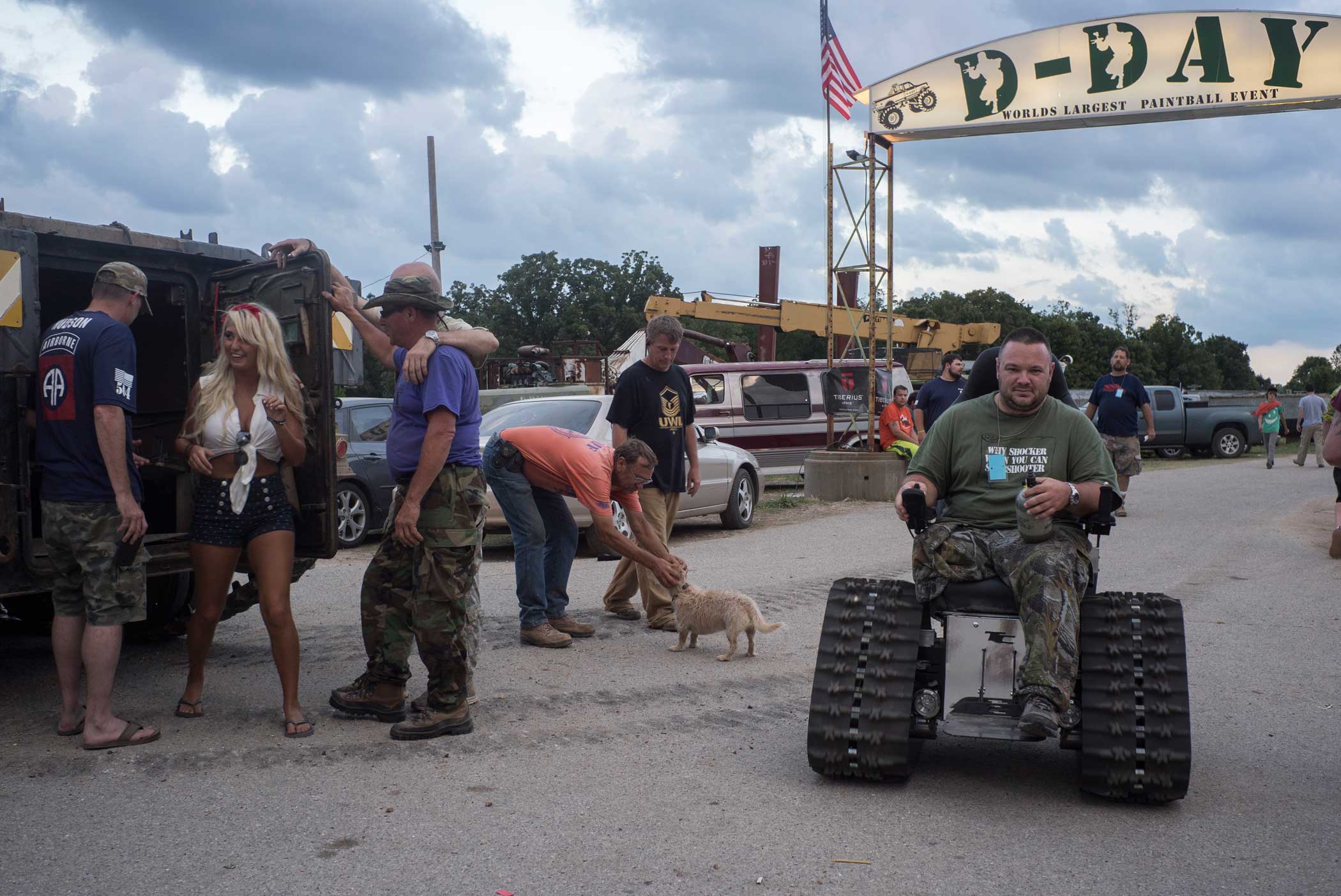 A young woman emerges from an operating M113 Armored Personnel Carrier that gives rides around the D-Day Adventure Park. On the right, Chris  Balls  Schneider, an amputee and Iraq veteran, rides a wheelchair invented by Team Defiant, an organization created by disabled vets to build all terrain wheelchairs.