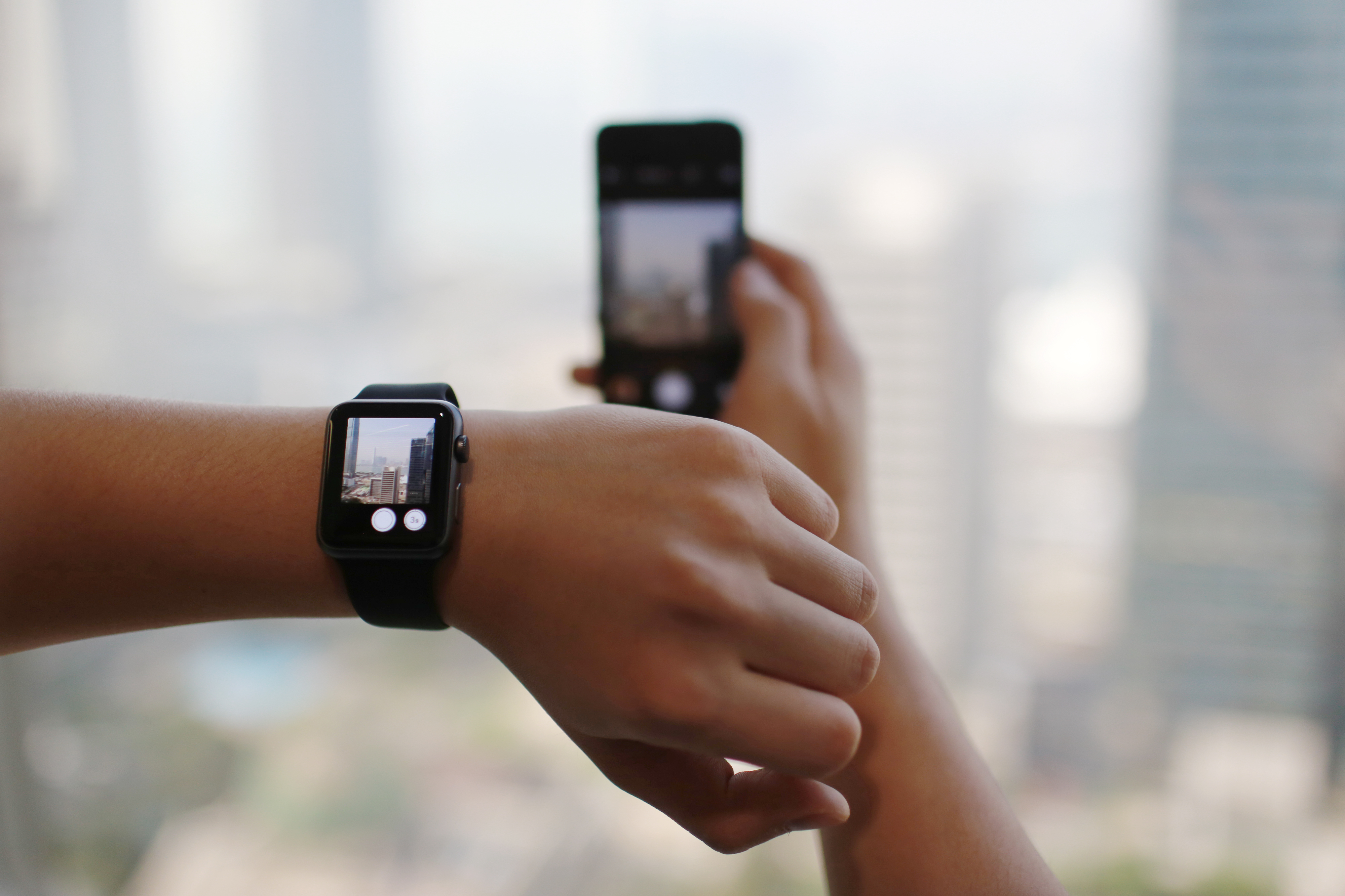A man uses the remote camera function on an Apple Watch Sport smartwatch as he holds an Apple iPhone 5s smartphone in an arranged photograph in Hong Kong, April 24, 2015. (Bloomberg — Getty Images)