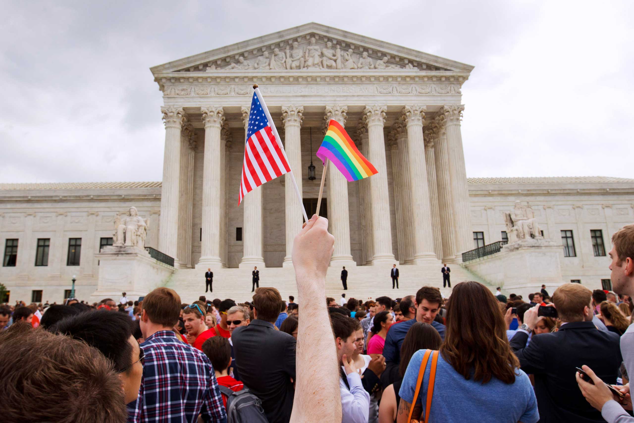 A man holds a U.S. and a rainbow flag outside the Supreme Court in Washington after the court legalized gay marriage nationwide. (Jacquelyn Martin — AP)