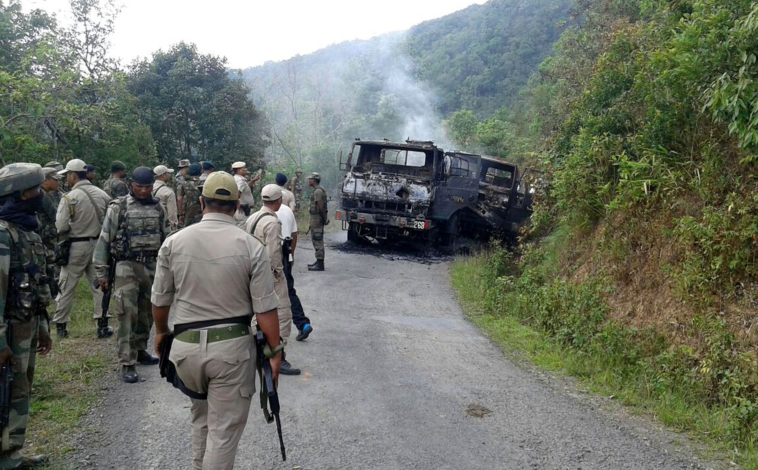 In this photograph taken on June 4, 2015, Indian security personnel stand alongside the smouldering vehicle wreckage at the scene of an attack on a military convoy in a remote area of Chandel district, about 120 kilometres (75 miles) southwest of northeastern Manipur's state capital Imphal. (STR—AFP/Getty Images)