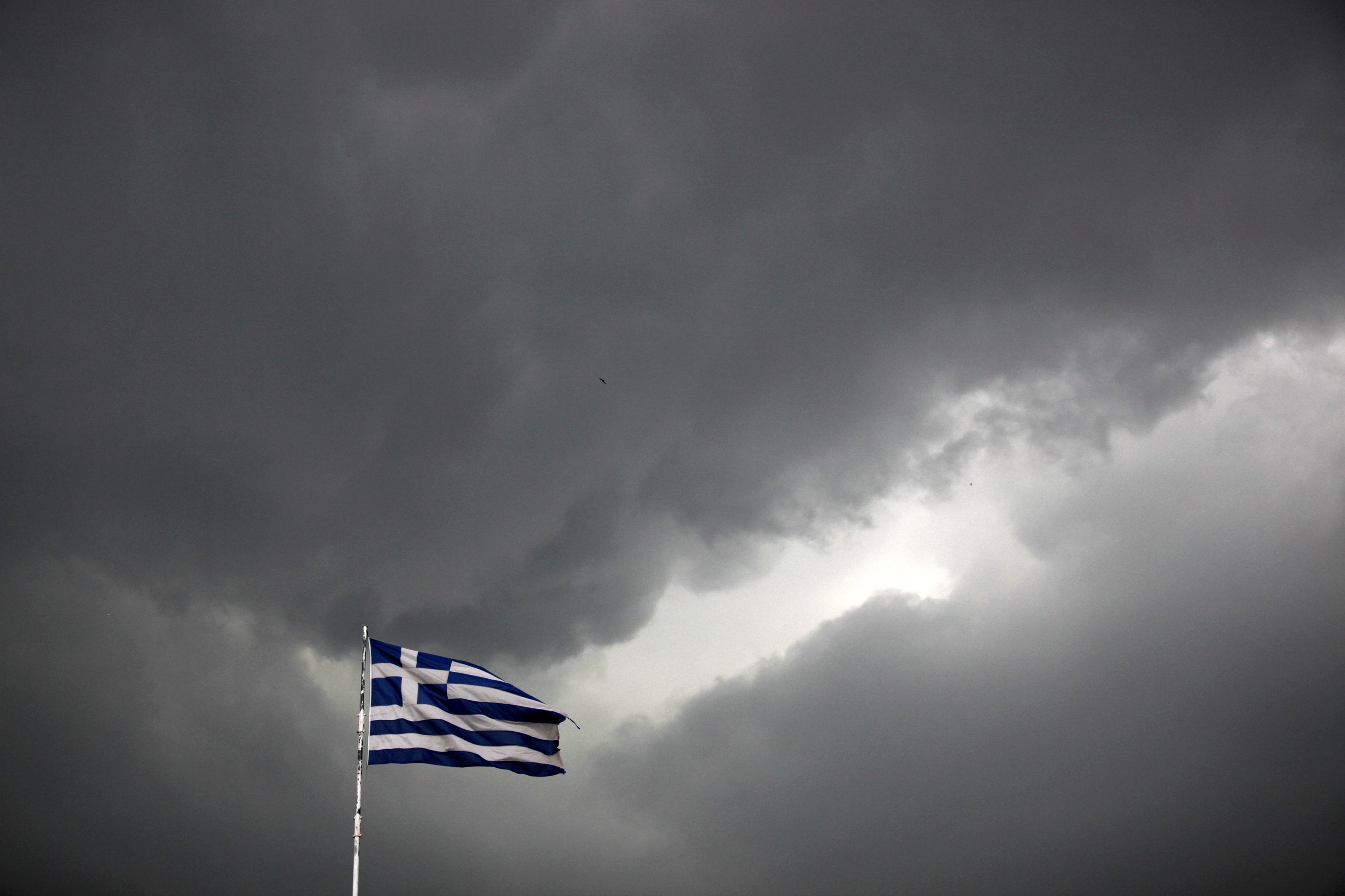 A Greek national flag flutters atop a building as dark clouds fill the sky in Athens on June 30, 2015. (Alkis Konstantinidis—Reuters)