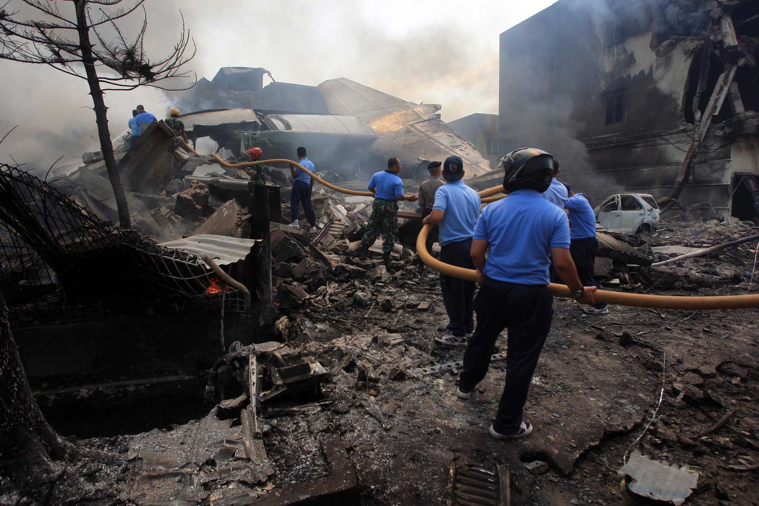 Rescuers extinguish a fire after a military airplane crashed during their search for victims in Medan, Indonesia, on June 30 2015.