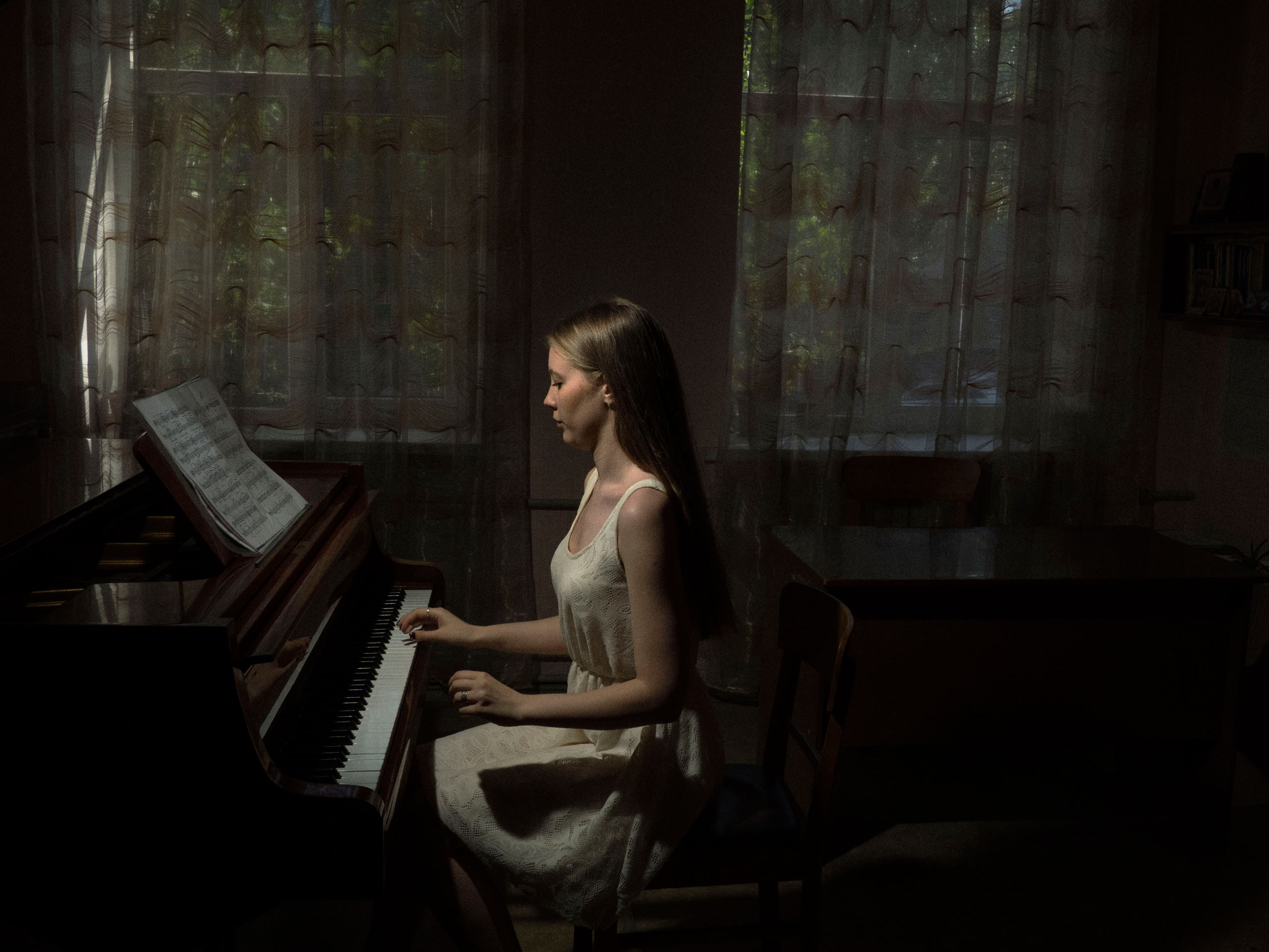 A student plays piano for her teacher during a year-end review at the music college. Mariupol, Ukraine. June 2, 2015.