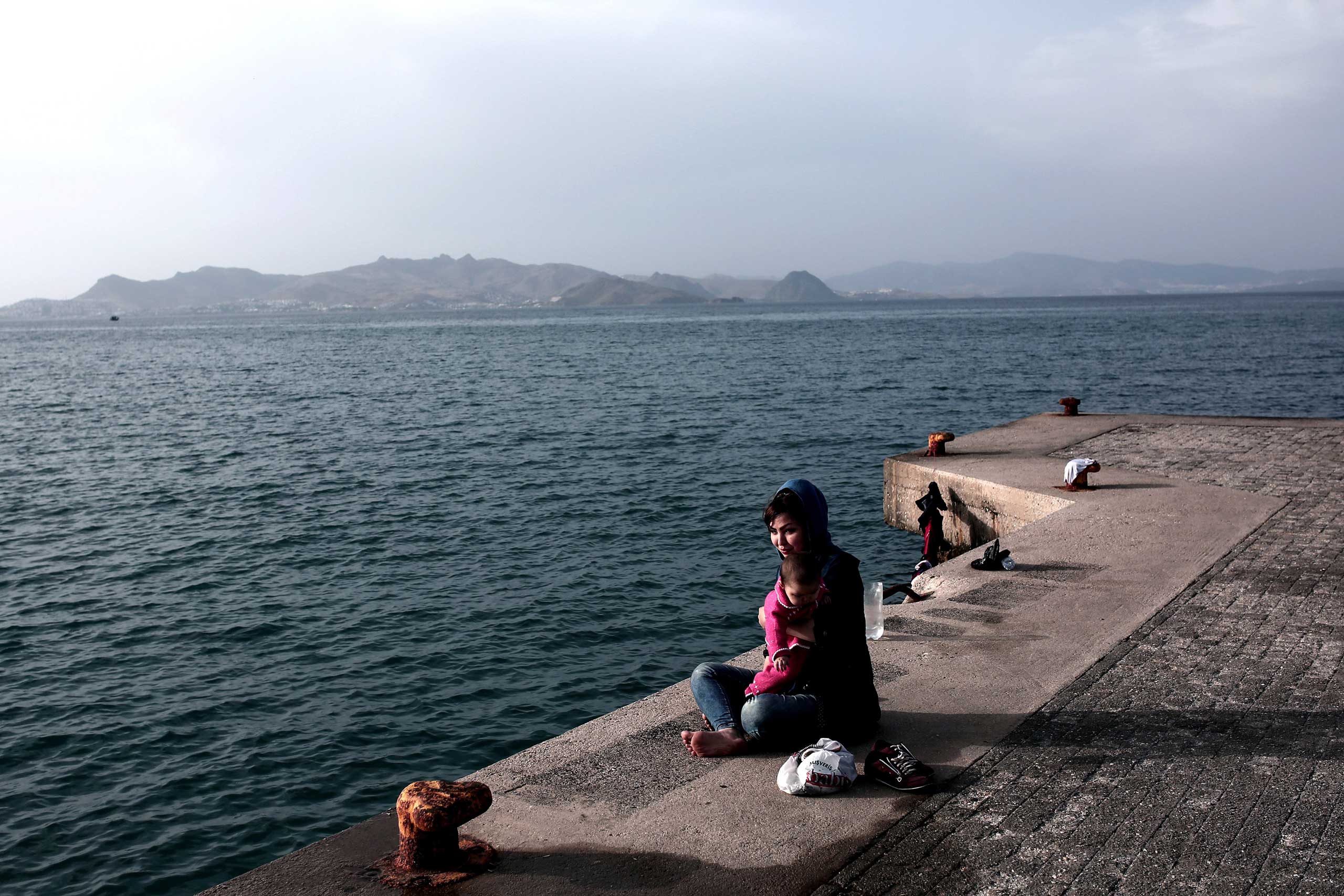 An Afghan woman sits with her child at a dock at the port of the Greek island of Kos on May 27, 2015.