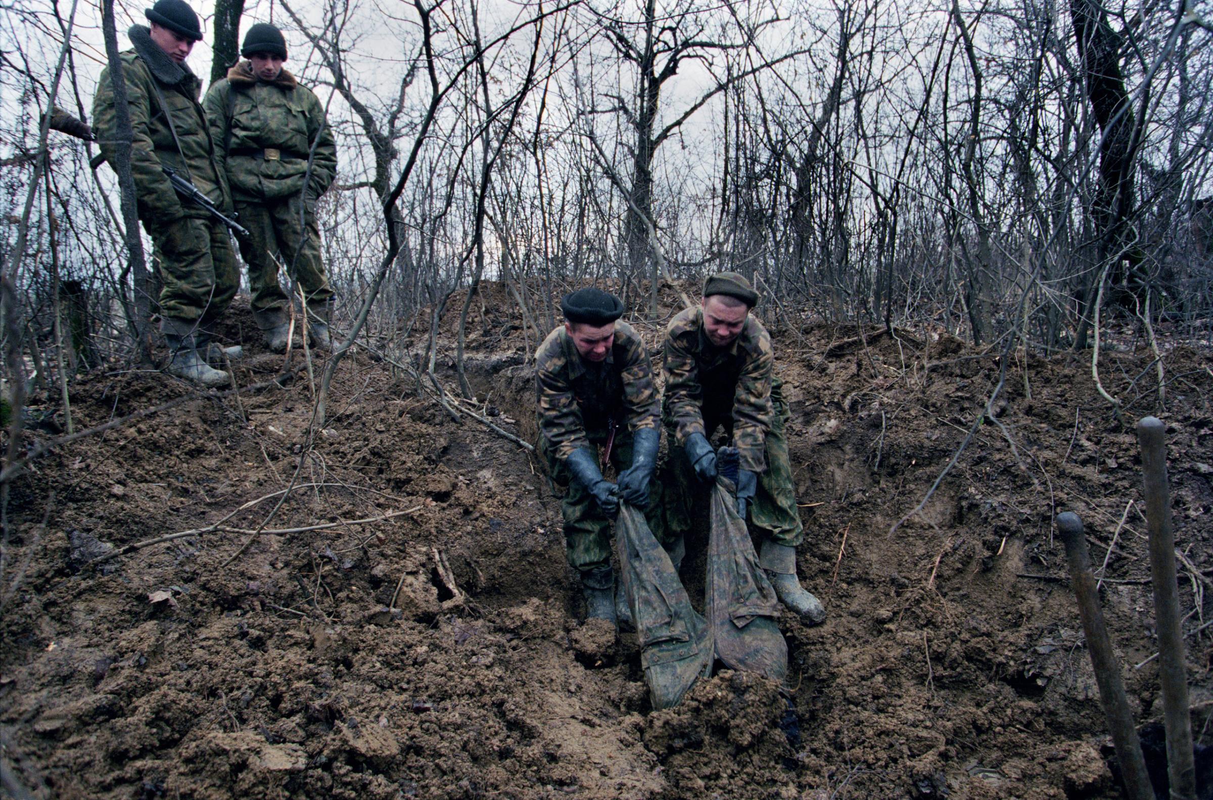 Russian forces uncover the body of a dead rebel in Tsentaroy. Chechnya, December 1999. Yuri Kozyrev—NOOR