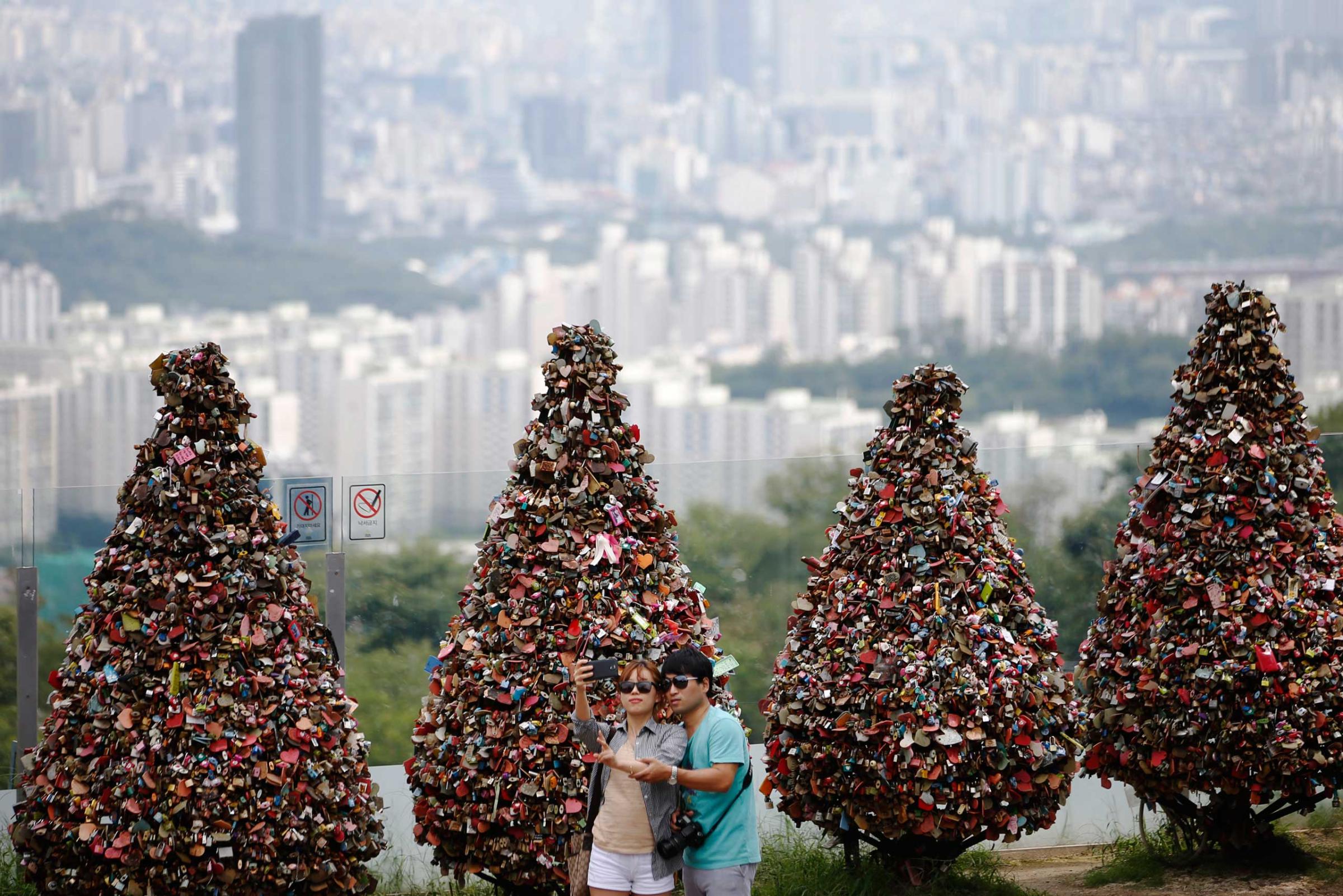Couple takes a selfie in front of trees covered with "love locks" at N Seoul Tower located atop Mt. Namsan in central Seoul