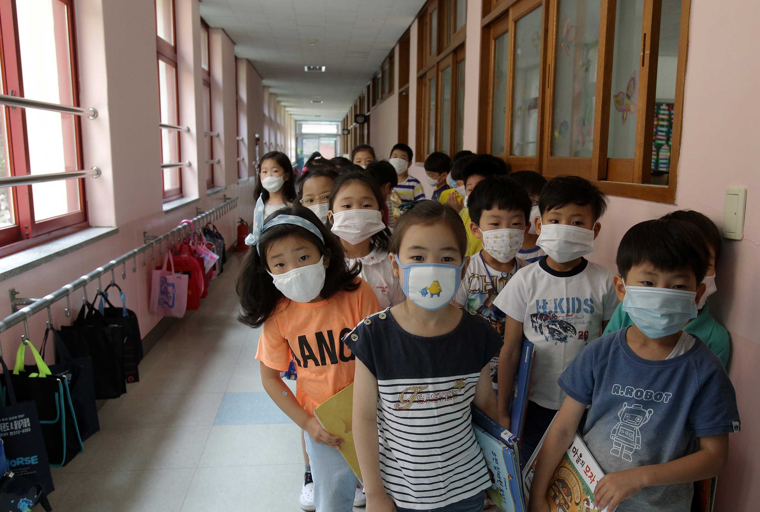 Elementary school students wear masks as a precaution against the MERS virus as they wait for a lesson to start at Midong Elementary School in Seoul on June 9, 2015.