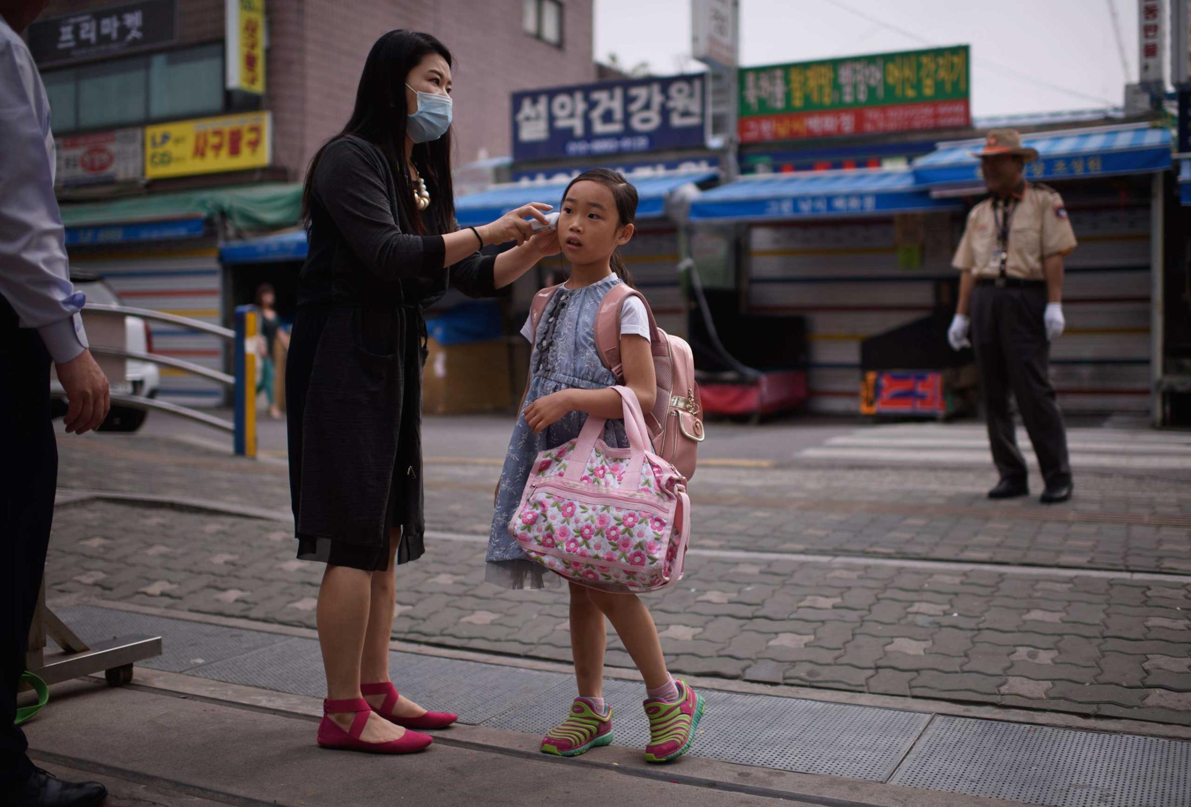 A student has her temperature taken by a teacher outside the Sungshin elementary school in Seoul on June 8, 2015.