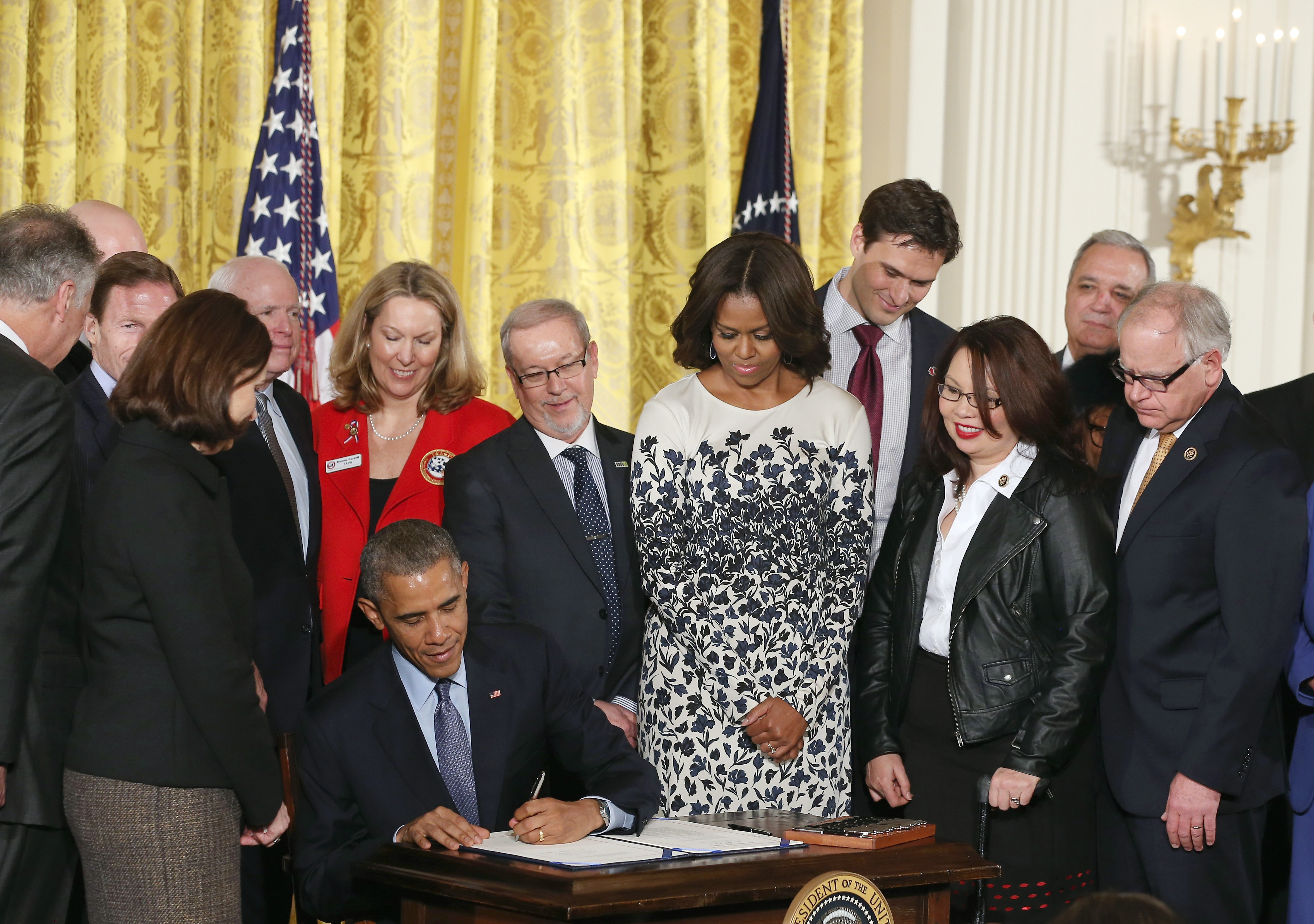 President Barack Obama signs the Clay Hunt Suicide Prevention for American Veterans Act while flanked by First Lady Michelle Obama and members of Congress during an event in the East Room of the White House in Washington on Feb. 12, 2015.