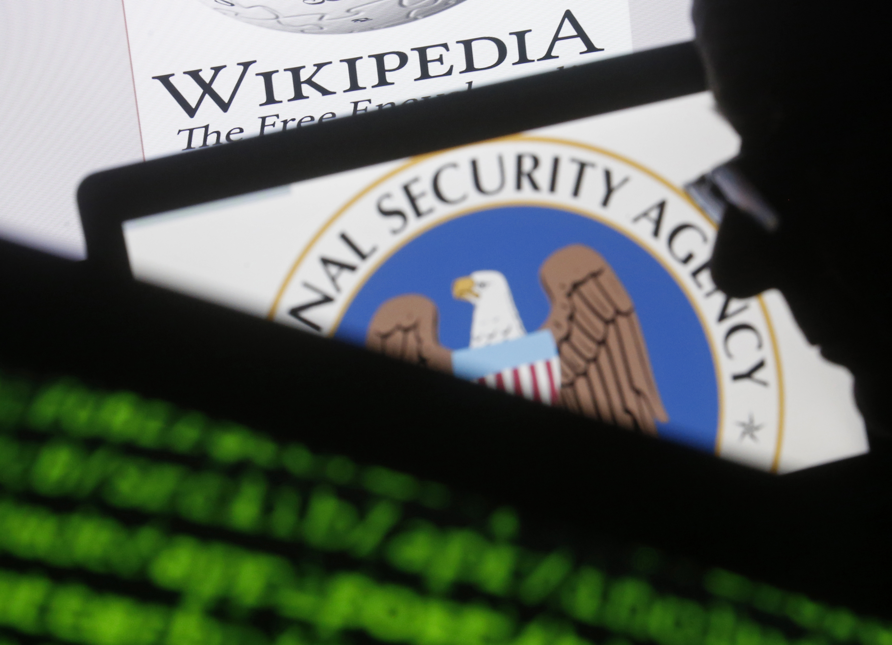 A man is seen near cyber code and the U.S. National Security Agency logo in this photo illustration taken in Sarajevo