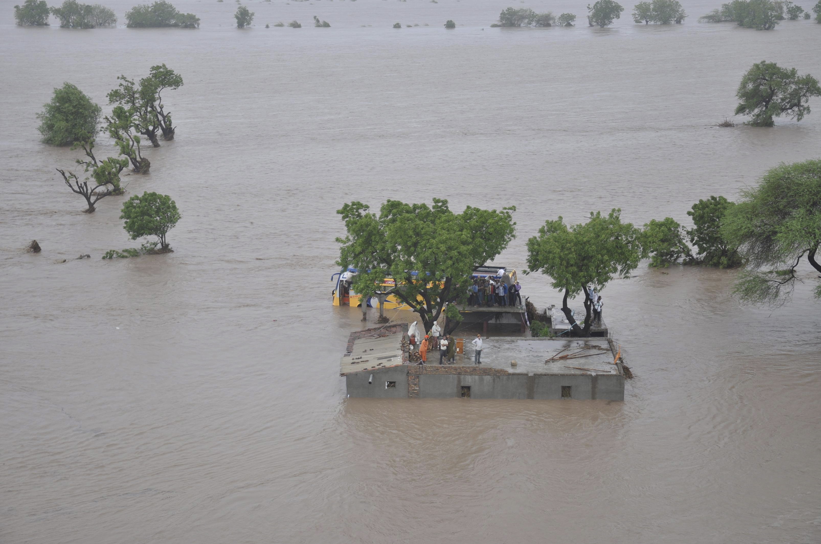 An aerial view shows flood victims standing atop their submerged houses in Amreli