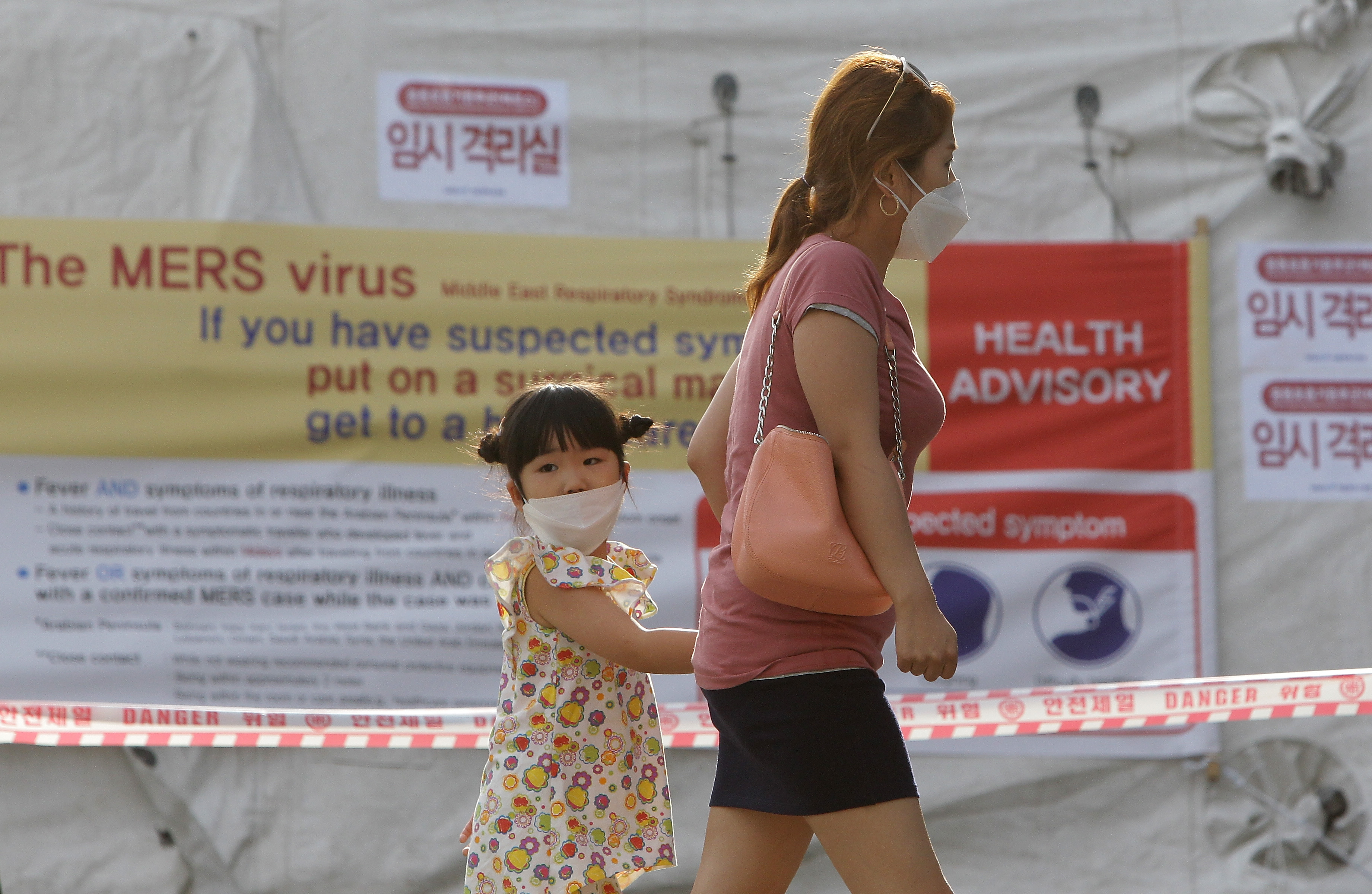 Visitors wearing masks walk in front of a health advisory sign about the MERS virus at a quarantine tent for people who could be infected with the MERS virus at Seoul National University Hospital on June 2 in Seoul, South Korea. (Chung Sung-Jun&mdash;2015 Getty Images)