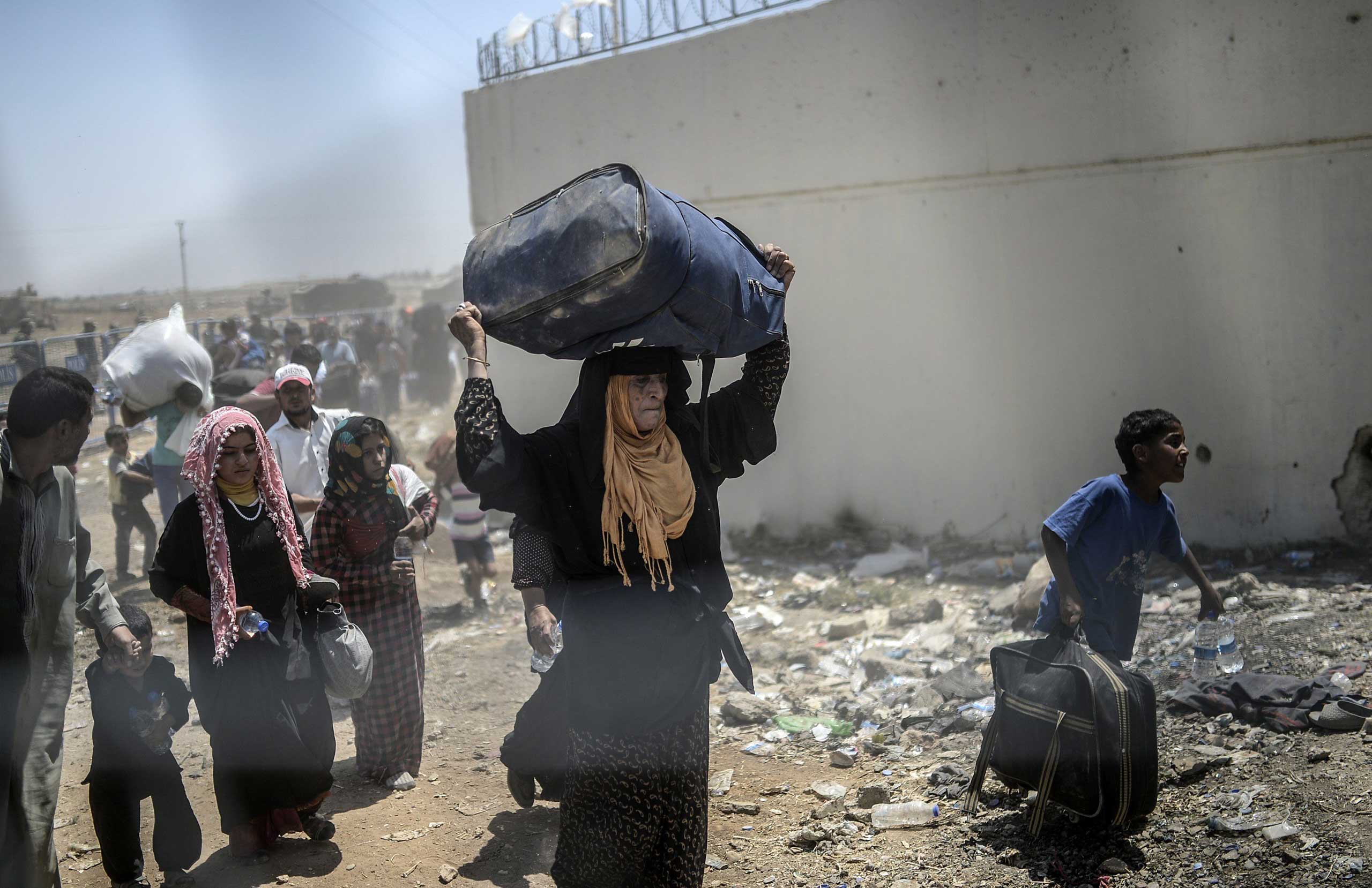 Syrians fleeing the war walk toward the border gates at the Akçakale crossing, in Sanliurfa province, on June 15, 2015.