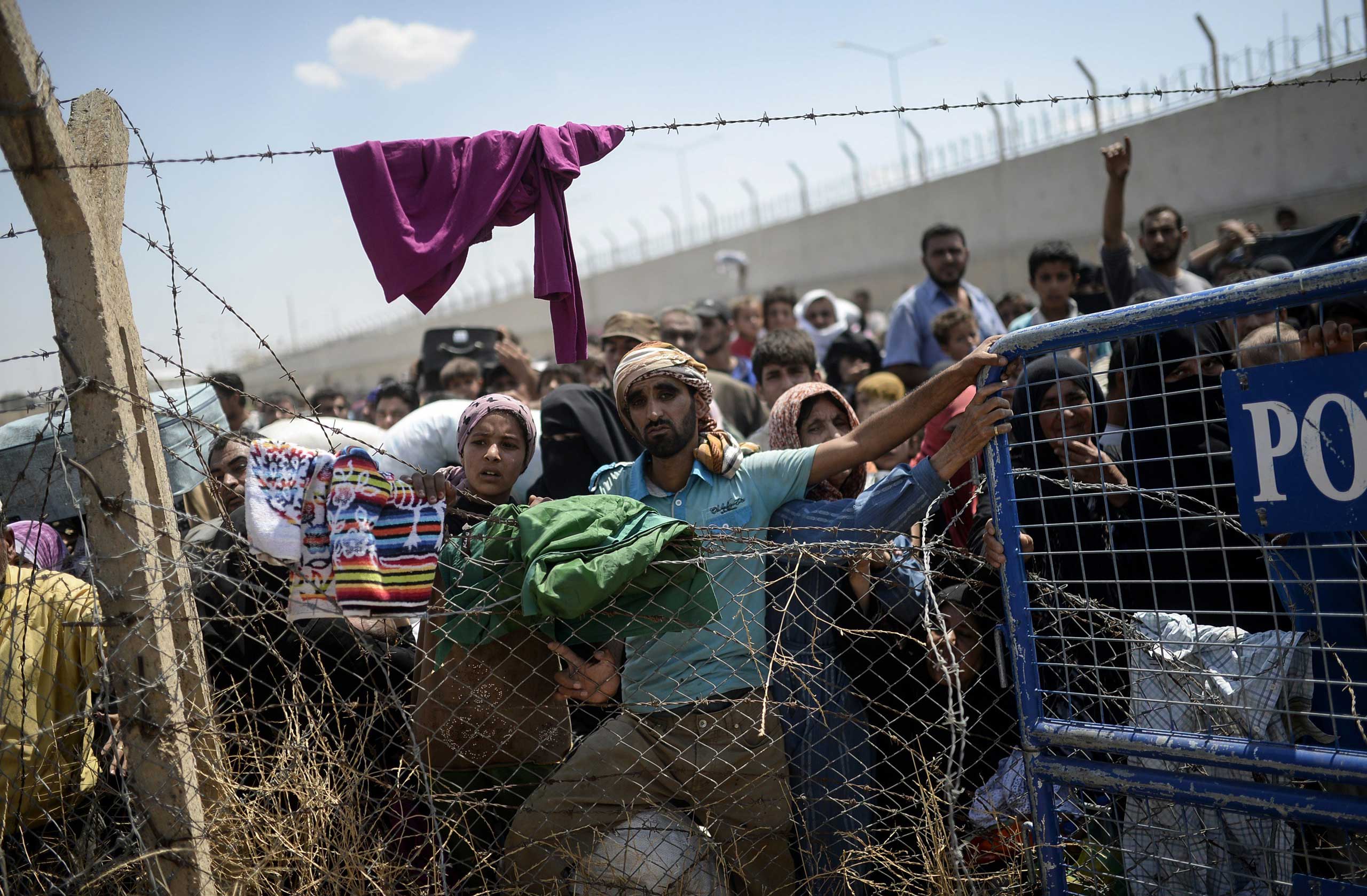 Syrians fleeing the war wait to enter Turkey near the Turkish border crossing at Akçakale, in Sanliurfa province, on June 15, 2015.