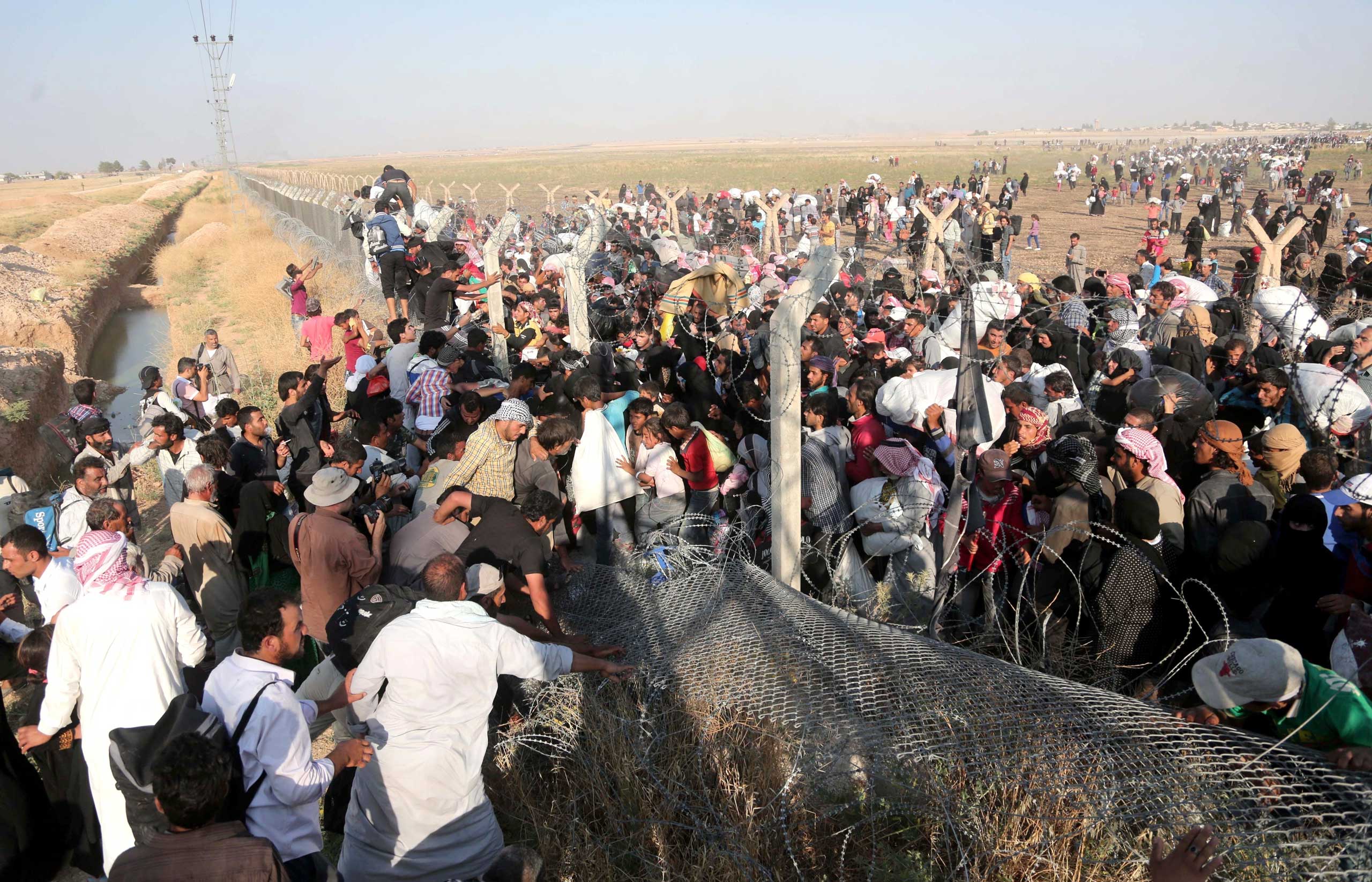 A group of Syrians, cross Turkish - Syrian border to take shelter in Turkey at Akçakale in Sanliurfa province on June 14, 2015.
