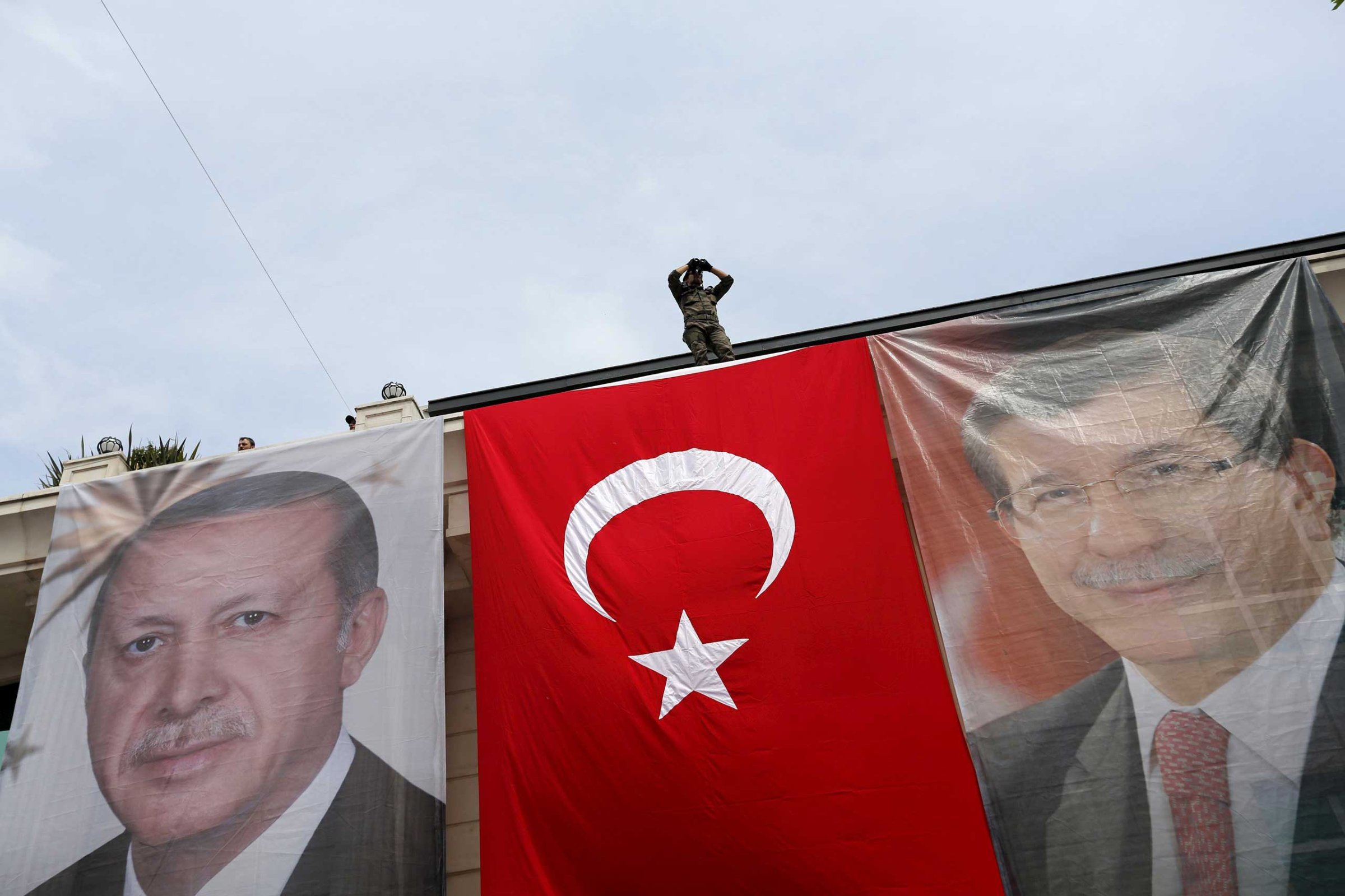 A special forces police officer takes security measures as he stands on top of a building where the portraits of Turkey's President Tayyip Erdogan, Prime Minister Ahmet Davutoglu and a Turkish flag are displayed in Istanbul on June 3, 2015.