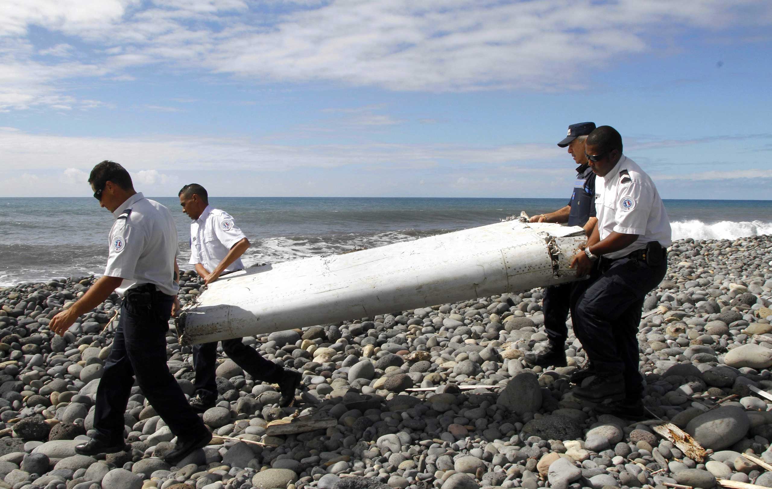 Officers carrying pieces of debris from an unidentified aircraft apparently washed ashore in Saint-Andre de la Reunion, eastern La Reunion island, France, on July 29, 2015.