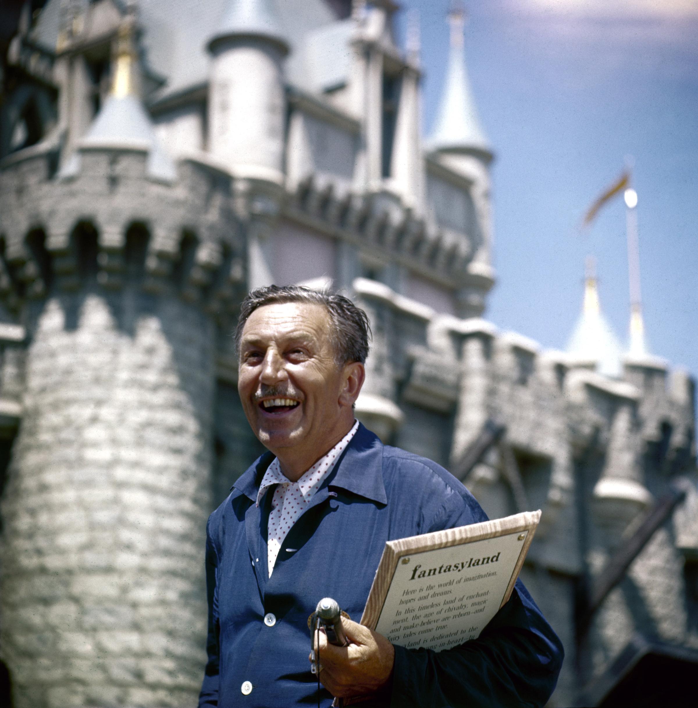 Walt Disney standing in front of Fantasyland Castle at Disneyland.