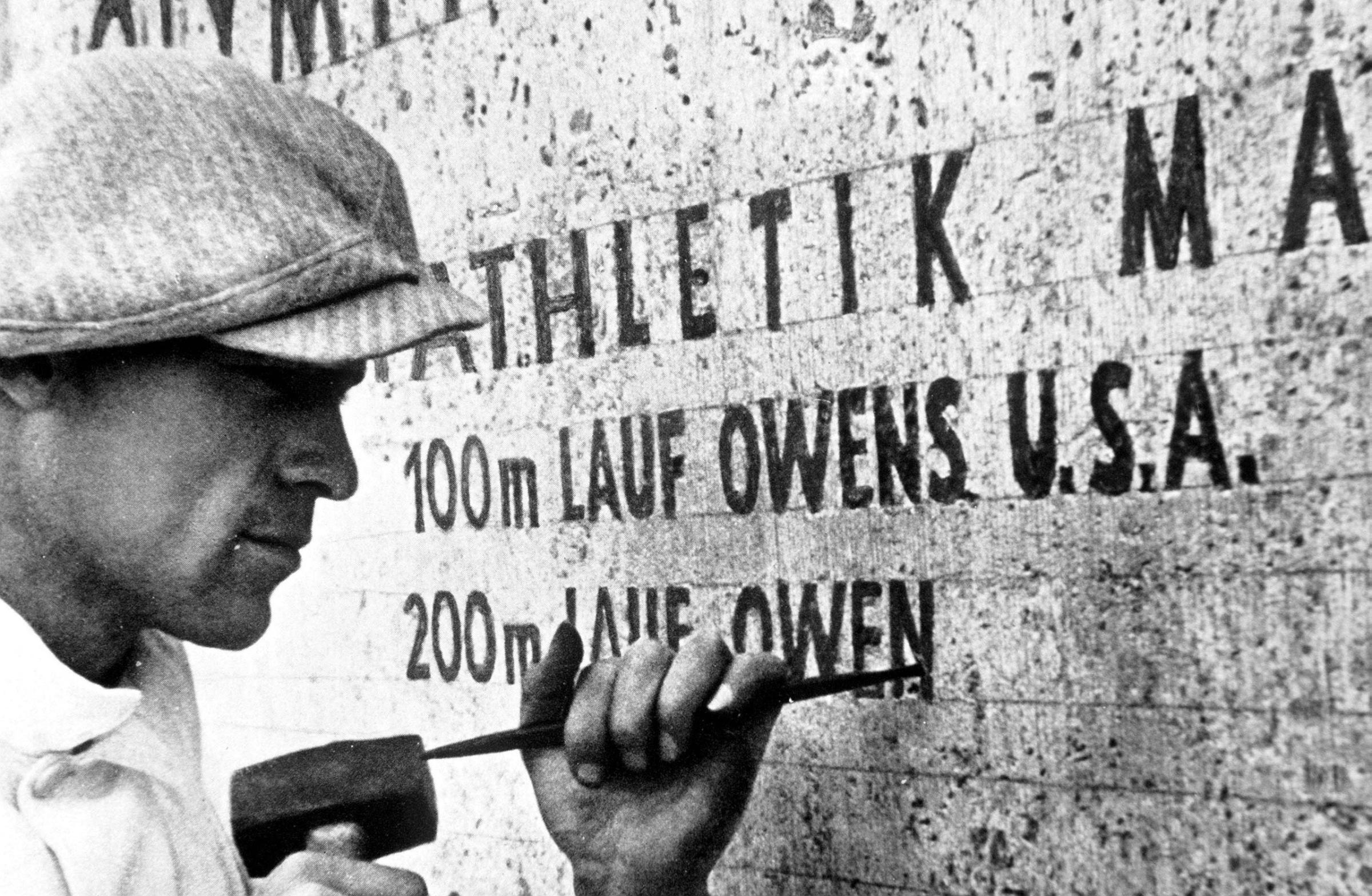 1936 Olympic Games, Berlin, Germany, A stonemason at work records the feat of USA's Jesse Owens, winner of four gold medals in the Games.