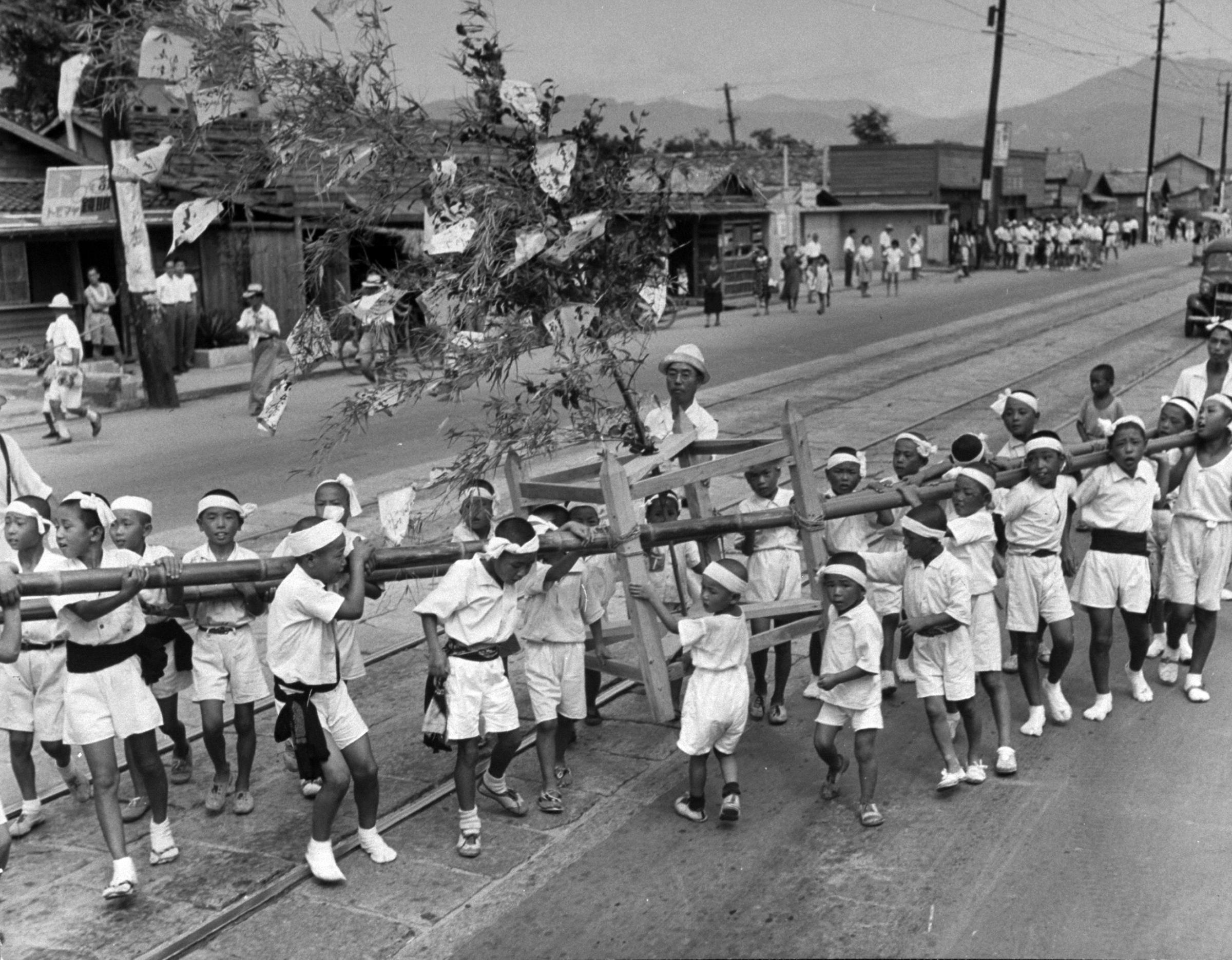 Boys carrying tree float in parade during Peace Festival in Hiroshima on anniversary of bomb dropping.
