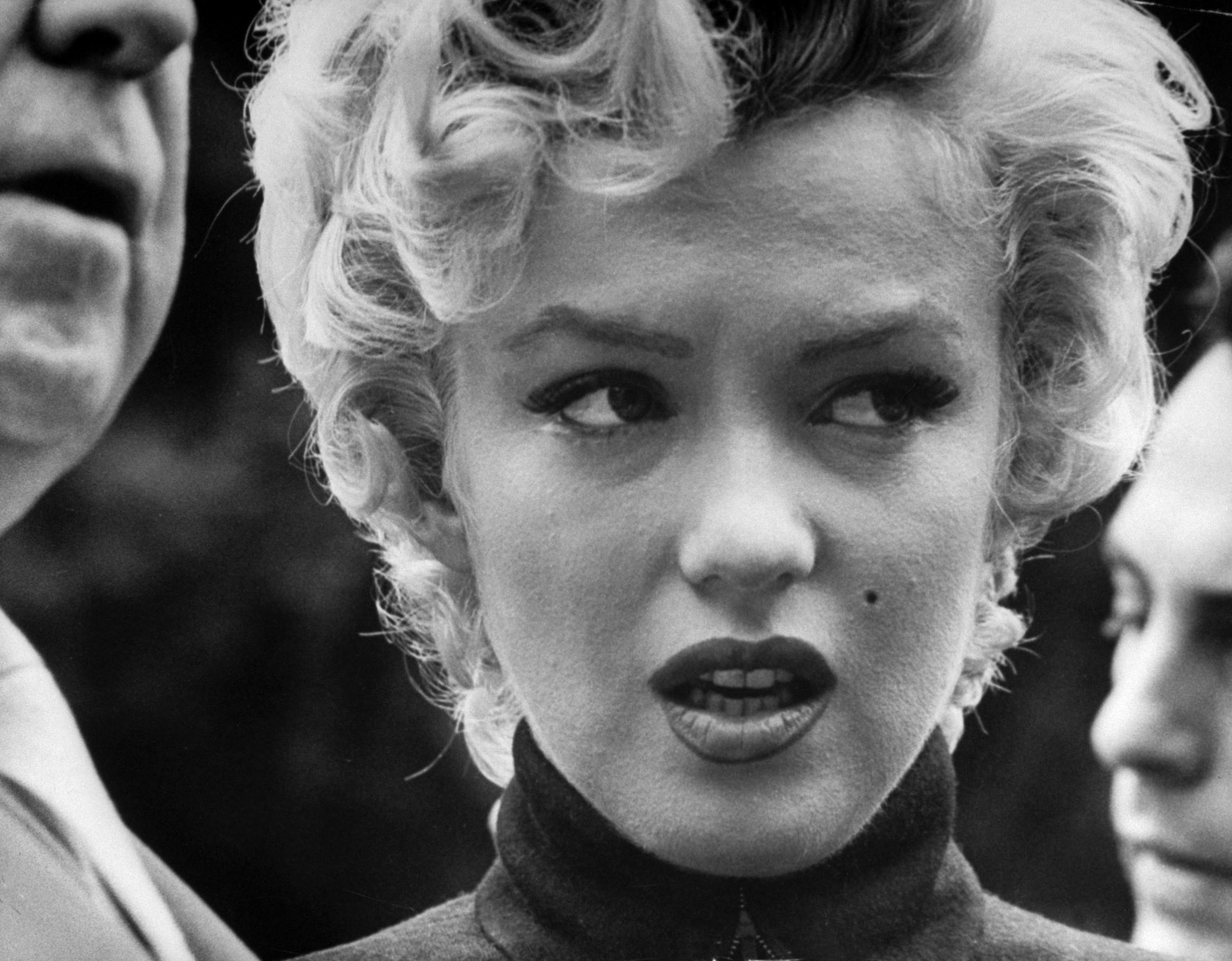 Tearful actress Marilyn Monroe coming out in front of home to face dozens of reporters after announcement of her divorce fr. baseball great Joe DiMaggio, 1954.