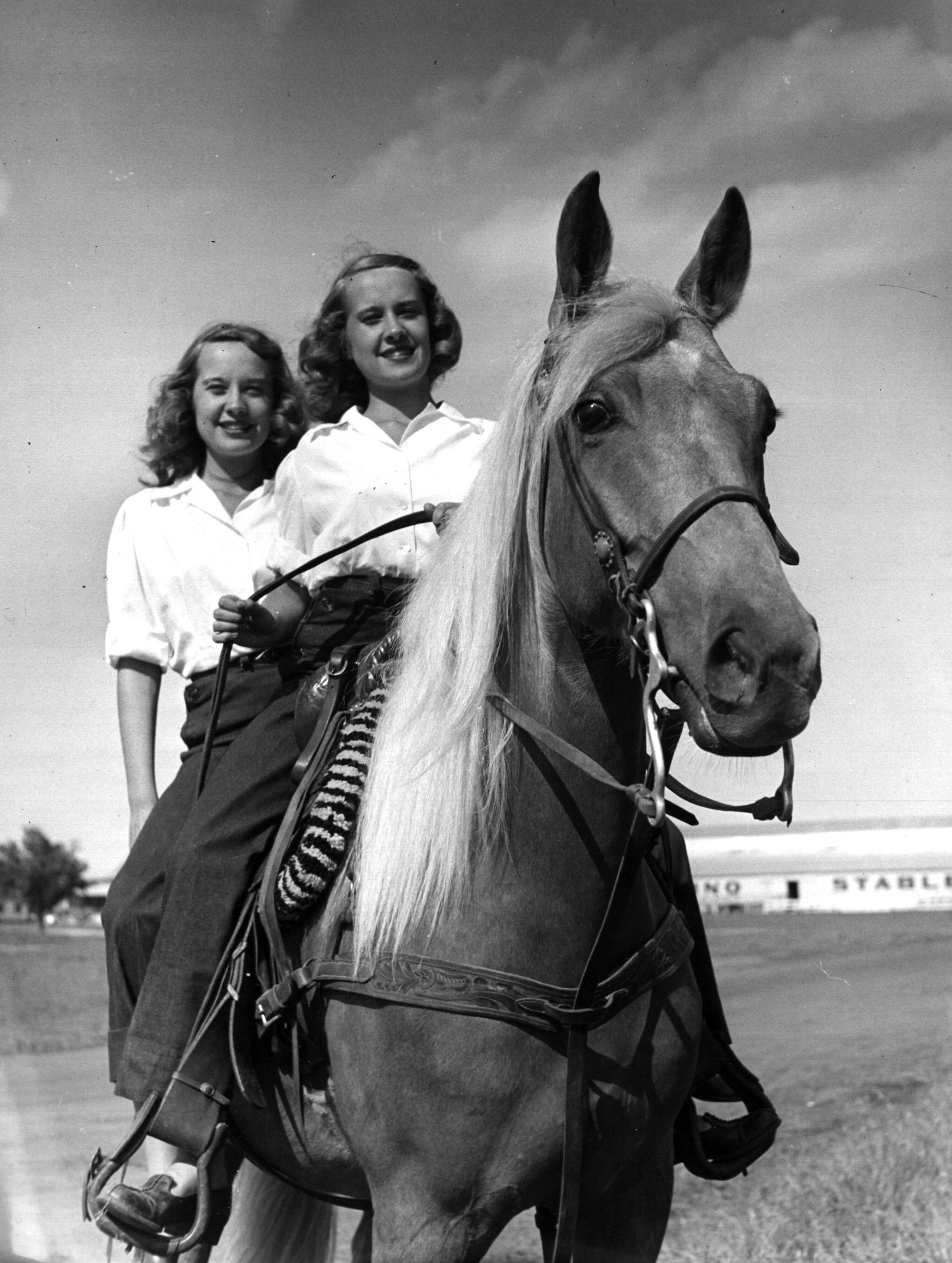 Identical twins, Barbara and Betty Bounds riding a horse.