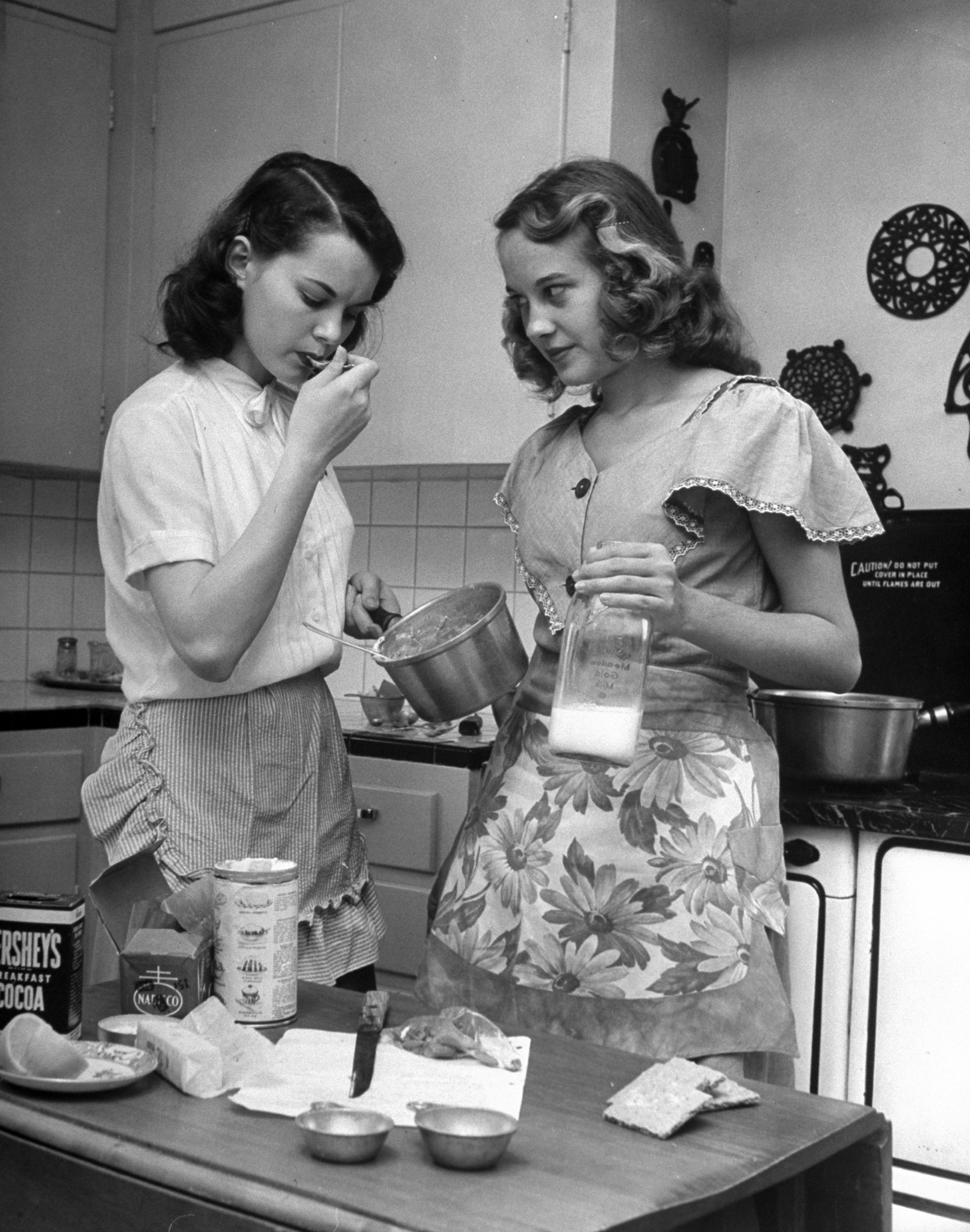 Teenager Nancy Churchwell tasting mixture for fudge cake as Barbara Bounds, 17, watches skeptically.