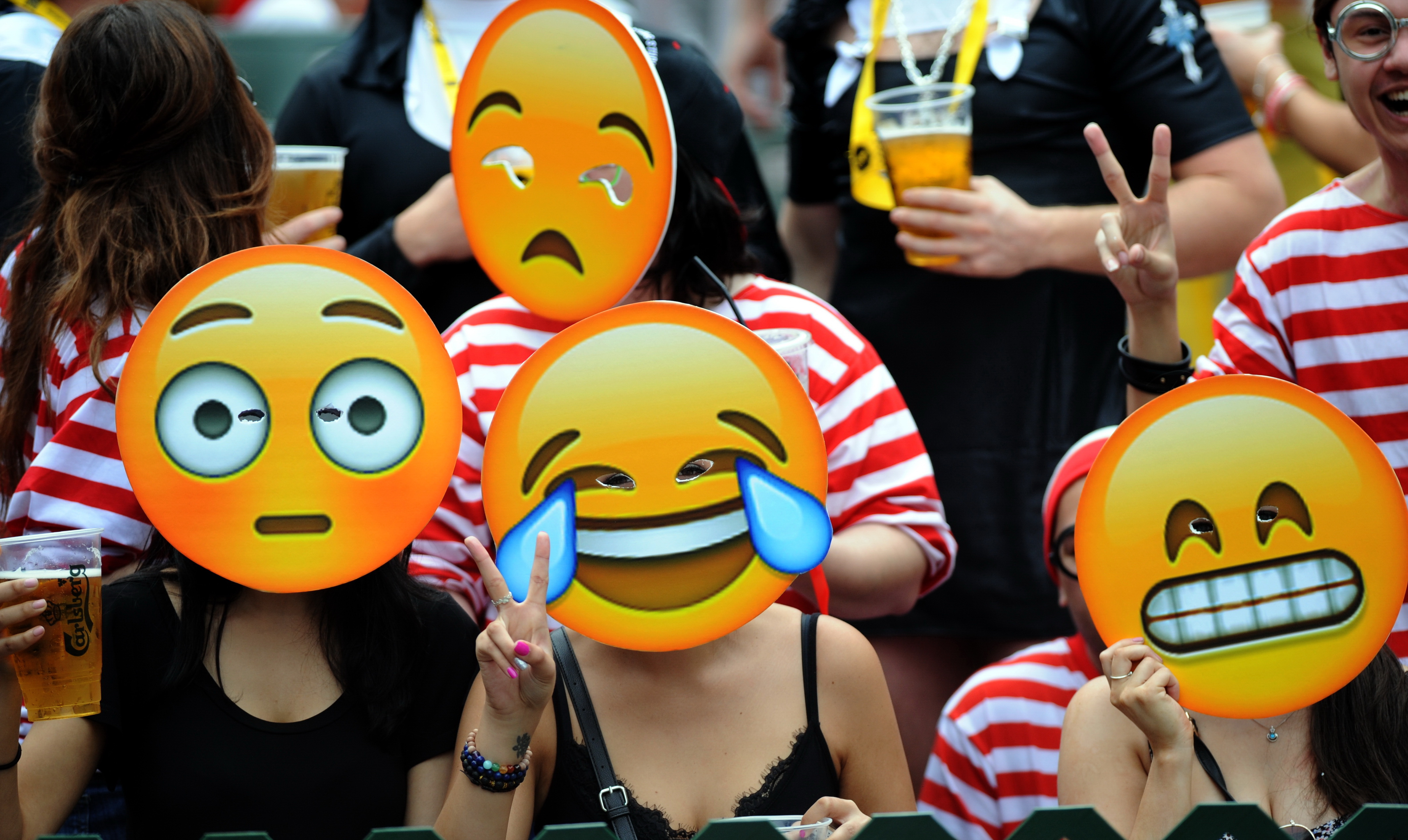 Fans wearing emoji masks watch a Hong Kong Seven rugby match in Hong Kong on March 28, 2015 (AP)