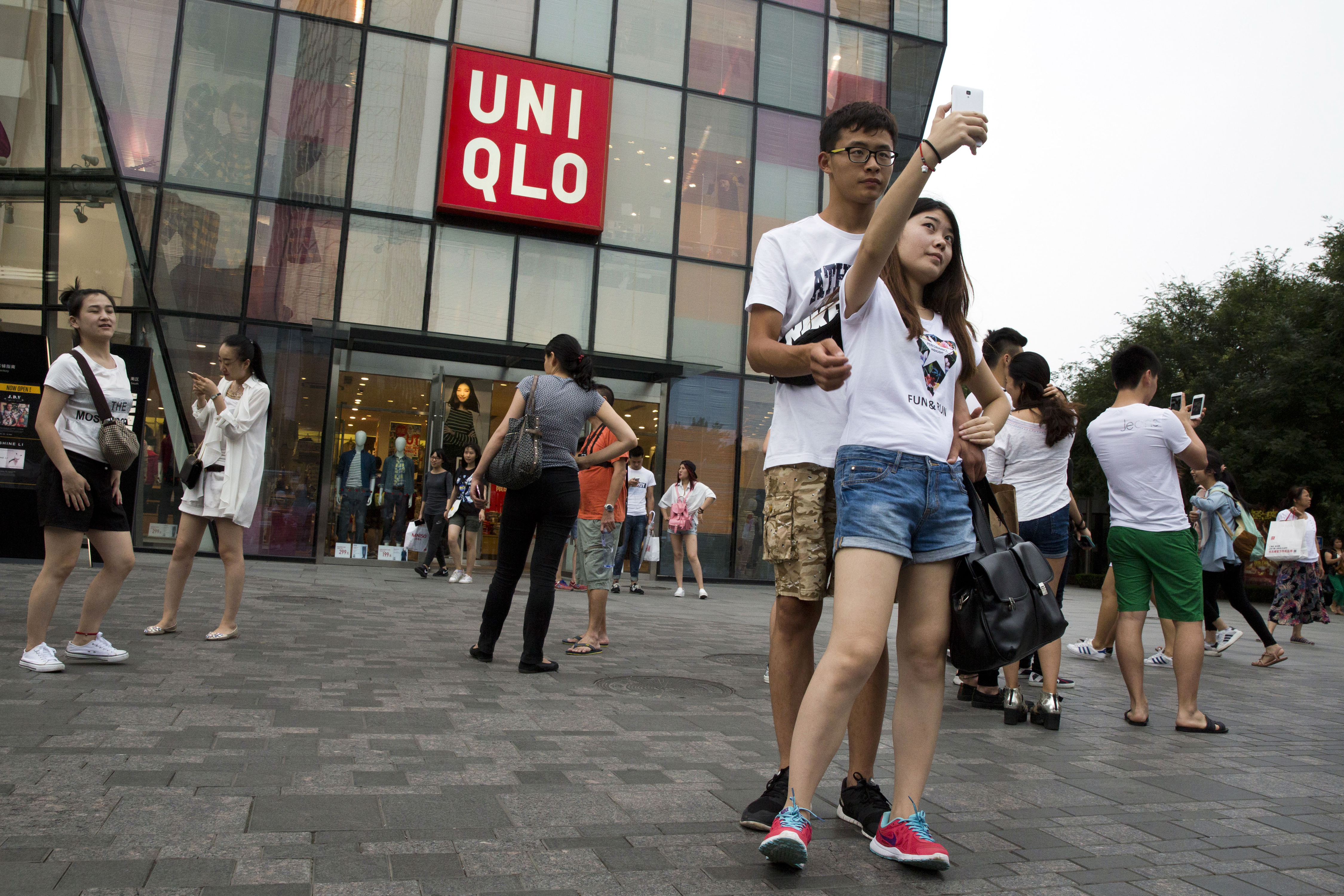 A Chinese couple take a selfie on July 16, 2015, outside the Uniqlo flagship store in Beijing, where a sex video purportedly taken inside one of its fitting rooms (Ng Han Guan—AP)