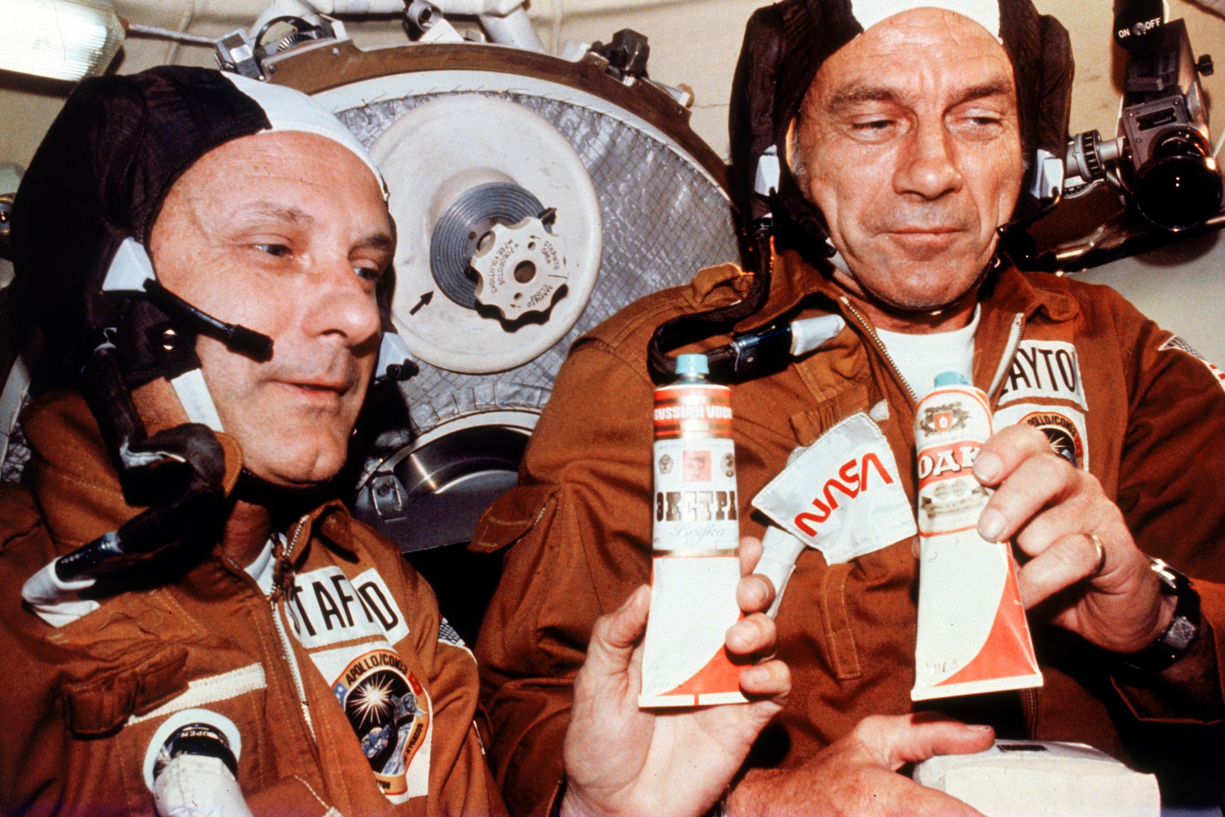 American astronauts Tom Stafford and Deke Slayton hold tubes of vodka given to them by Russian cosmonauts during their historic rendezvous and linkup of Apollo and Soyuz spacecraft.