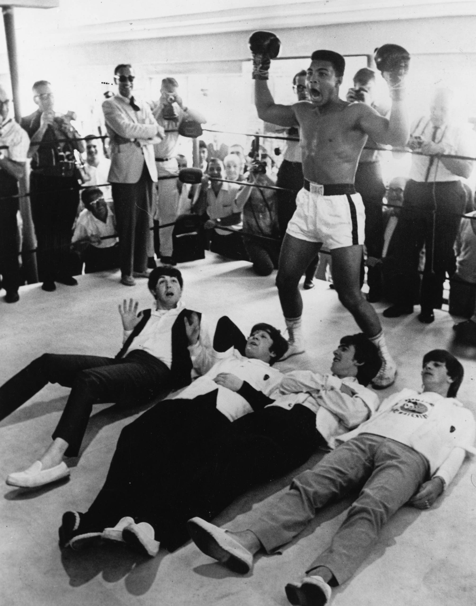 American heavyweight boxer Muhammad Ali (Cassius Clay) poses in the ring in a mock victory over The Beatles.