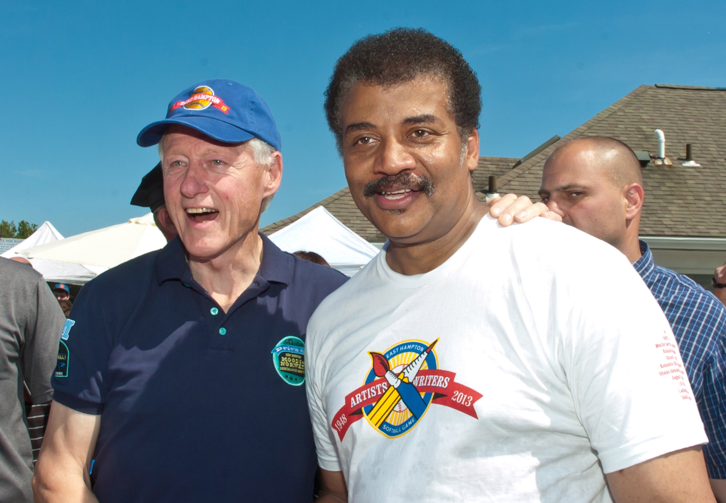 Former President Bill Clinton and Dr. Neil deGrasse Tyson attend the 65th Anniversary Artists & Writers Celebrity Softball Game at Herrick Park on Aug. 17, 2013 in East Hampton, New York.