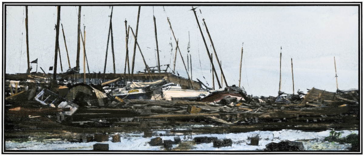 Hand-colored halftone reproduction of a photograph of oyster boats piled up at a Galveston wharf after the hurricane of 1900 (AP)