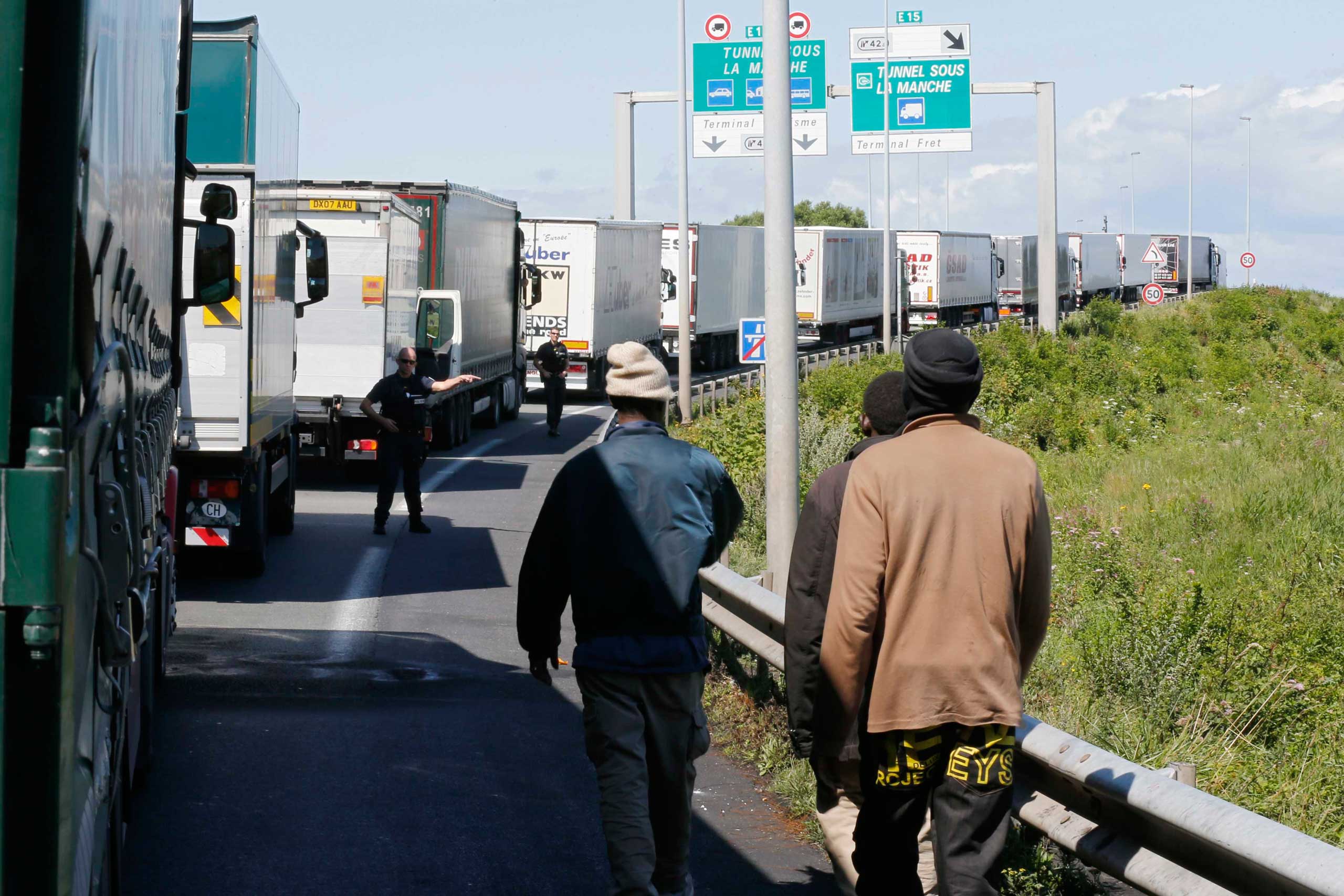 A French policeman signals to migrants to leave the road as lorries queue in Calais on July 29, 2015.