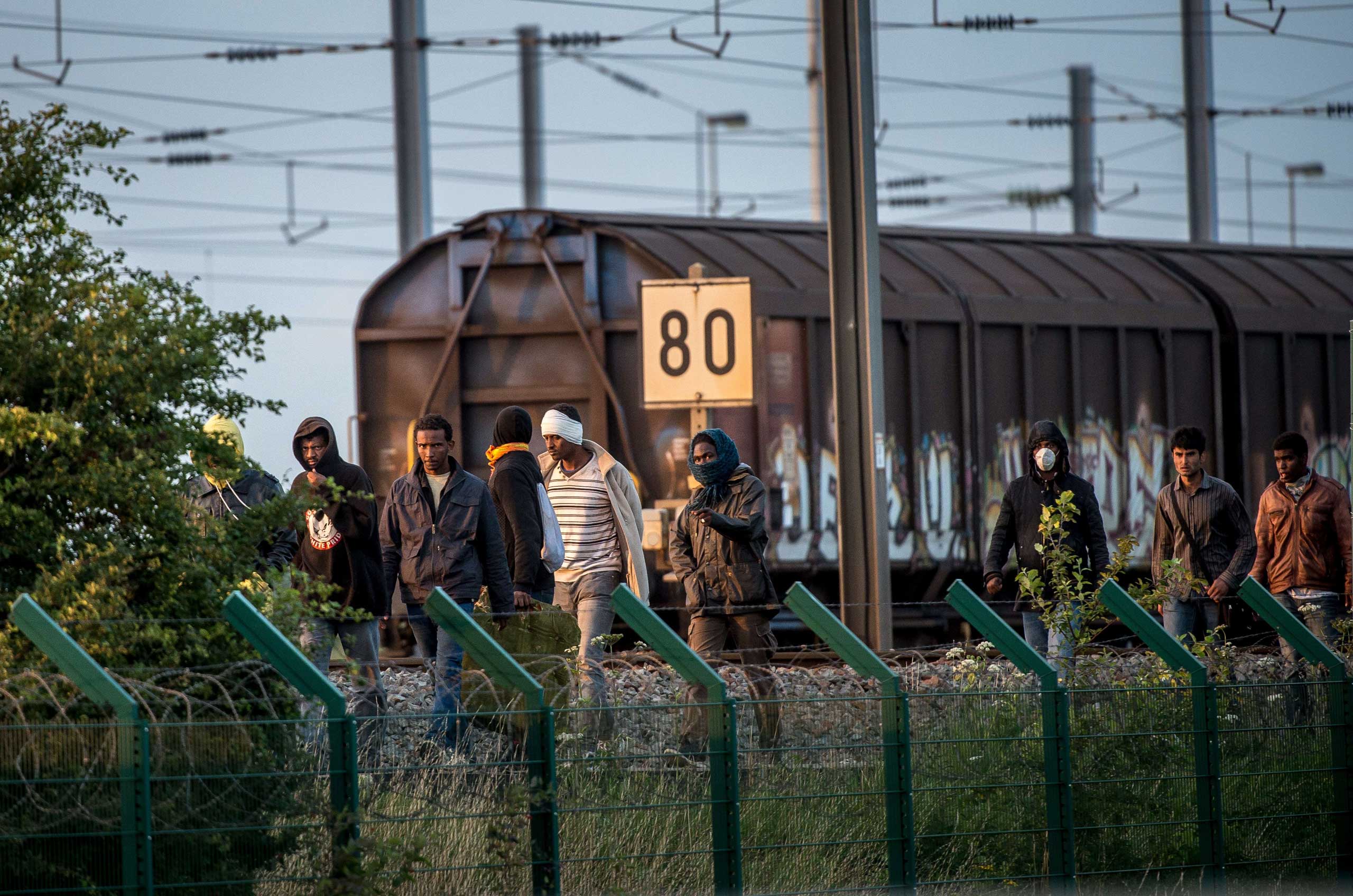 Migrants who successfully crossed the Eurotunnel terminal walk on the side of the railroad as they try to reach a shuttle to Great Britain,  in Frethun, northern France, on July 28, 2015.