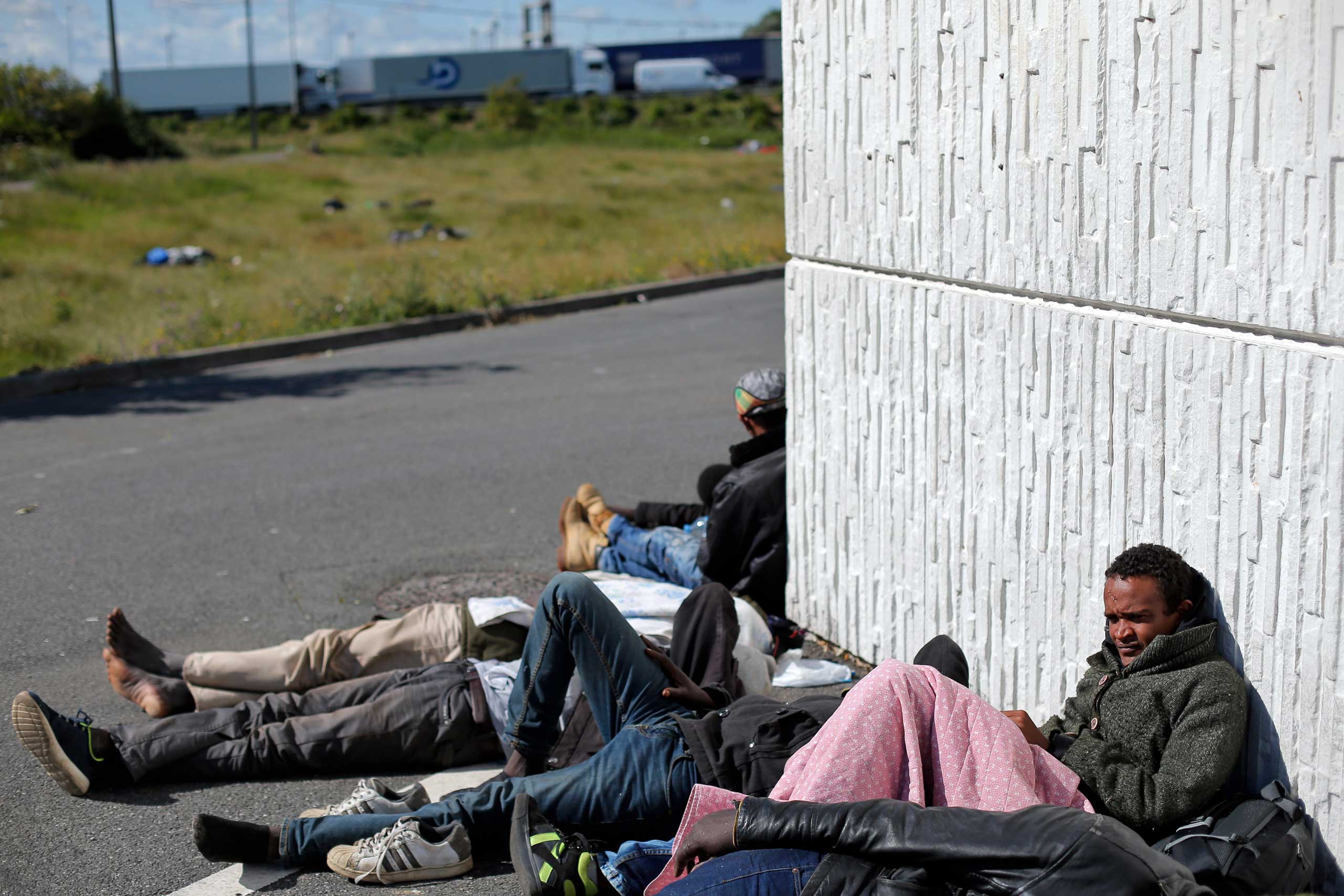 Migrants wait near a motorway leading to the ferry port to cross the English channel on July 29, 2015.