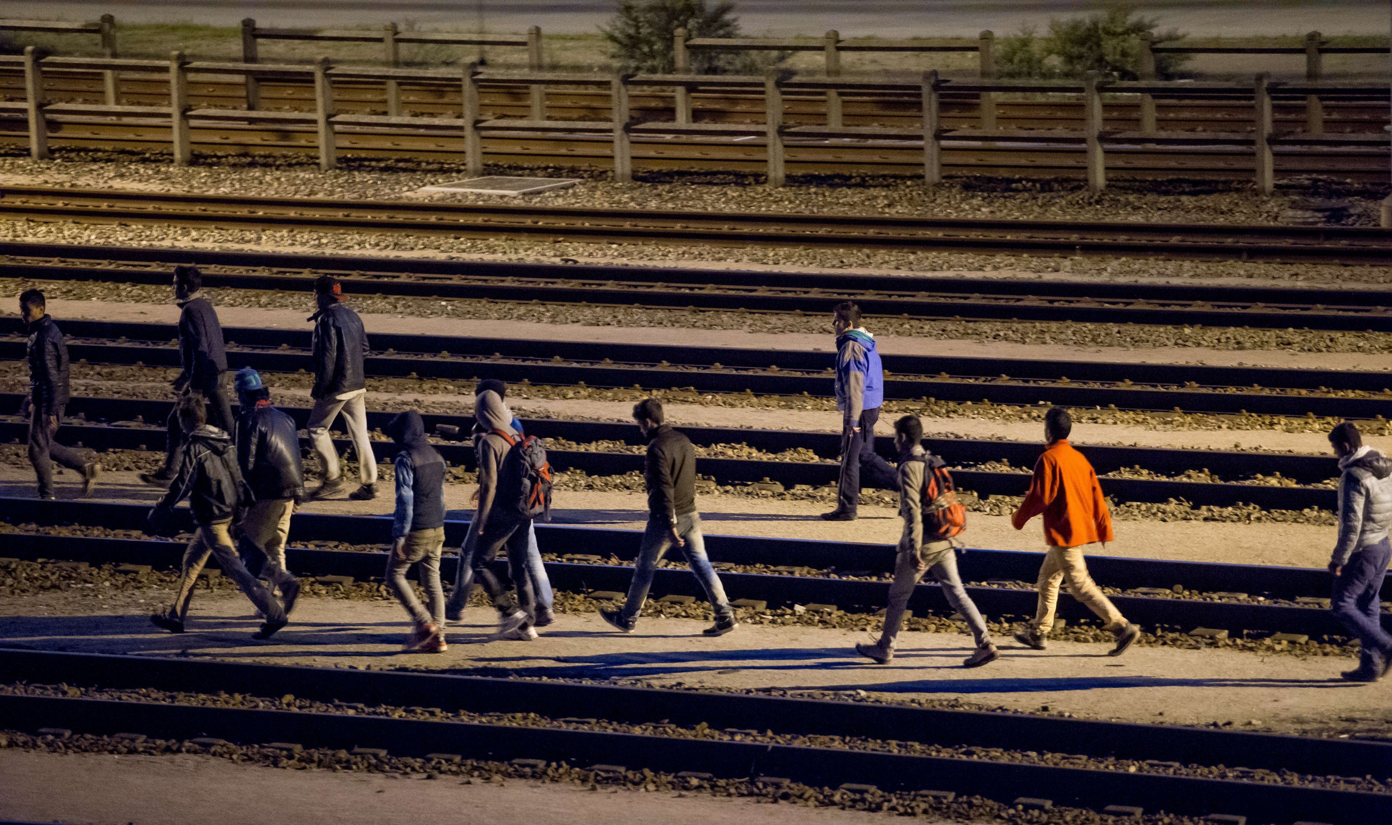 Migrants walk along railway tracks at the Eurotunnel terminal on July 28, 2015 in Calais-Frethun.
