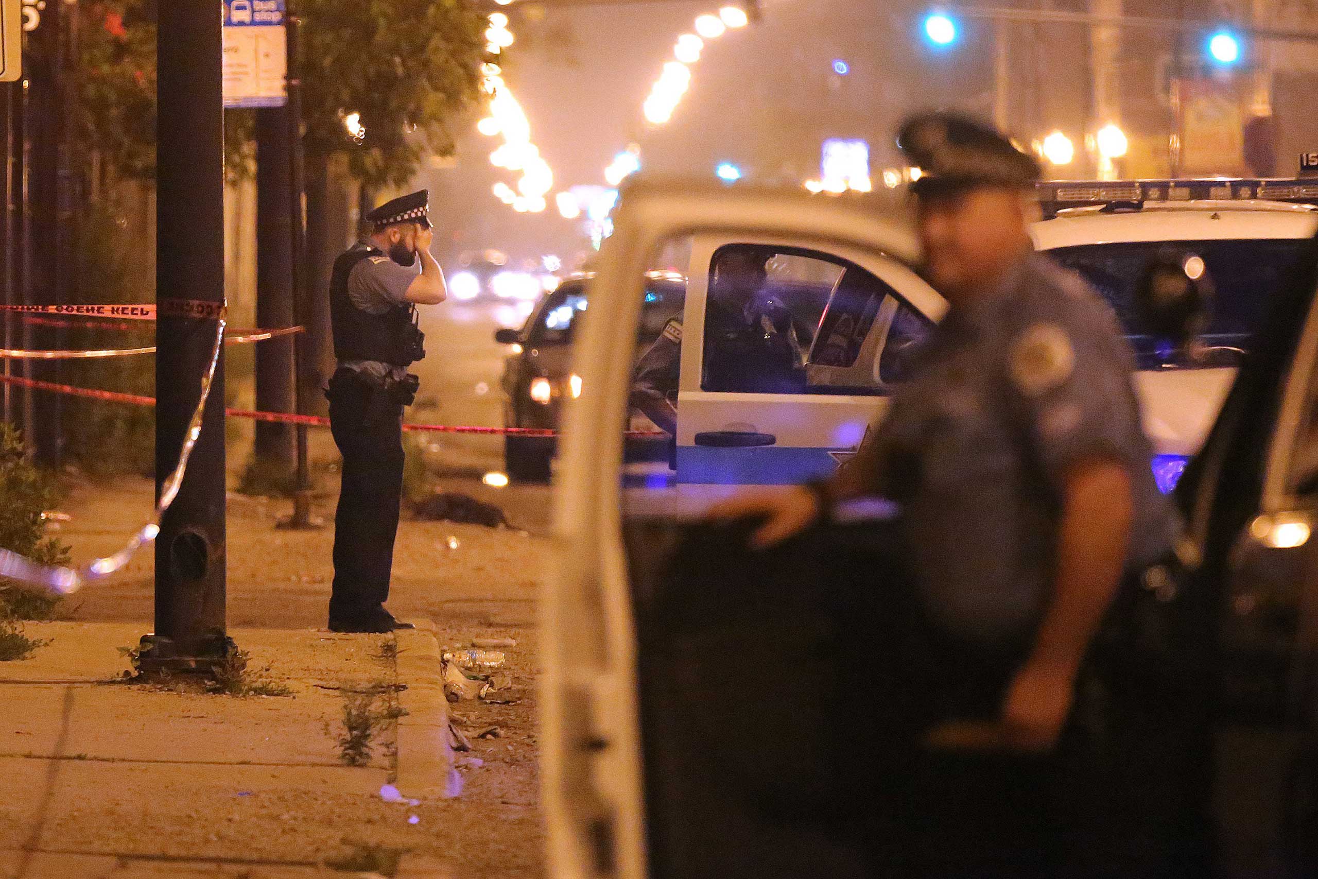 A police officer rests his hand on his forehead at the scene where a 23-year old man was shot in the early morning hours of July 6, 2015 in Chicago. (Anthony Souffle—Chicago Tribune/TNS/Sipa)