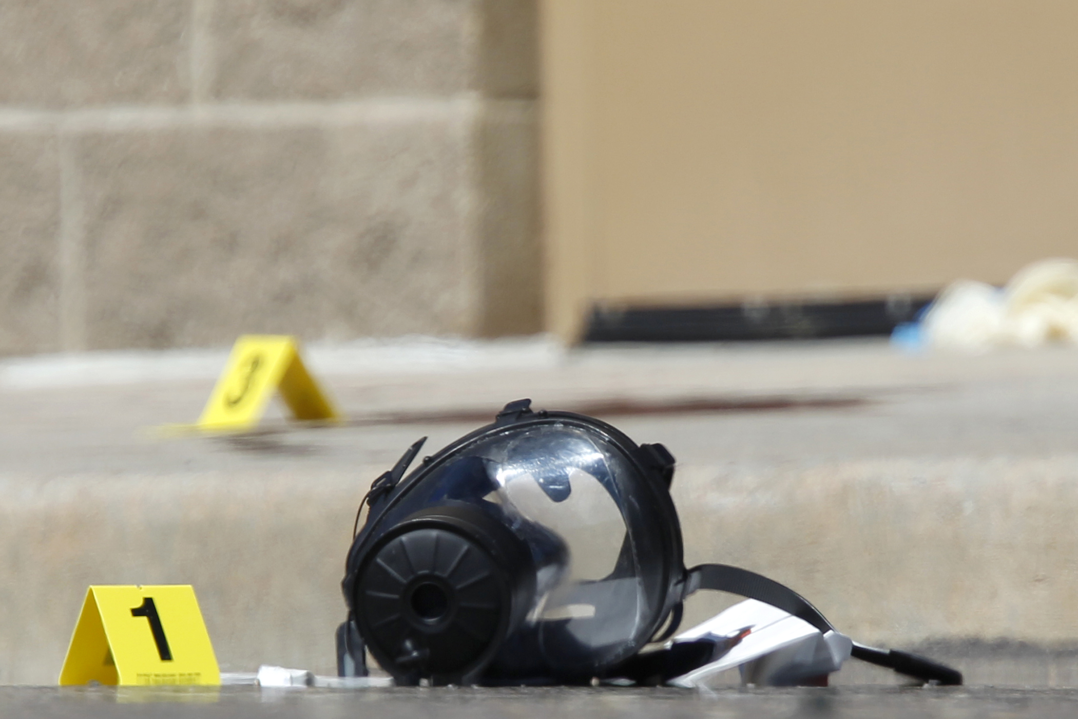 Yellow markers sit next to evidence, including a gas mask, as police investigate the scene outside the Century 16 movie theater in Aurora, Colo., July 20, 2012.