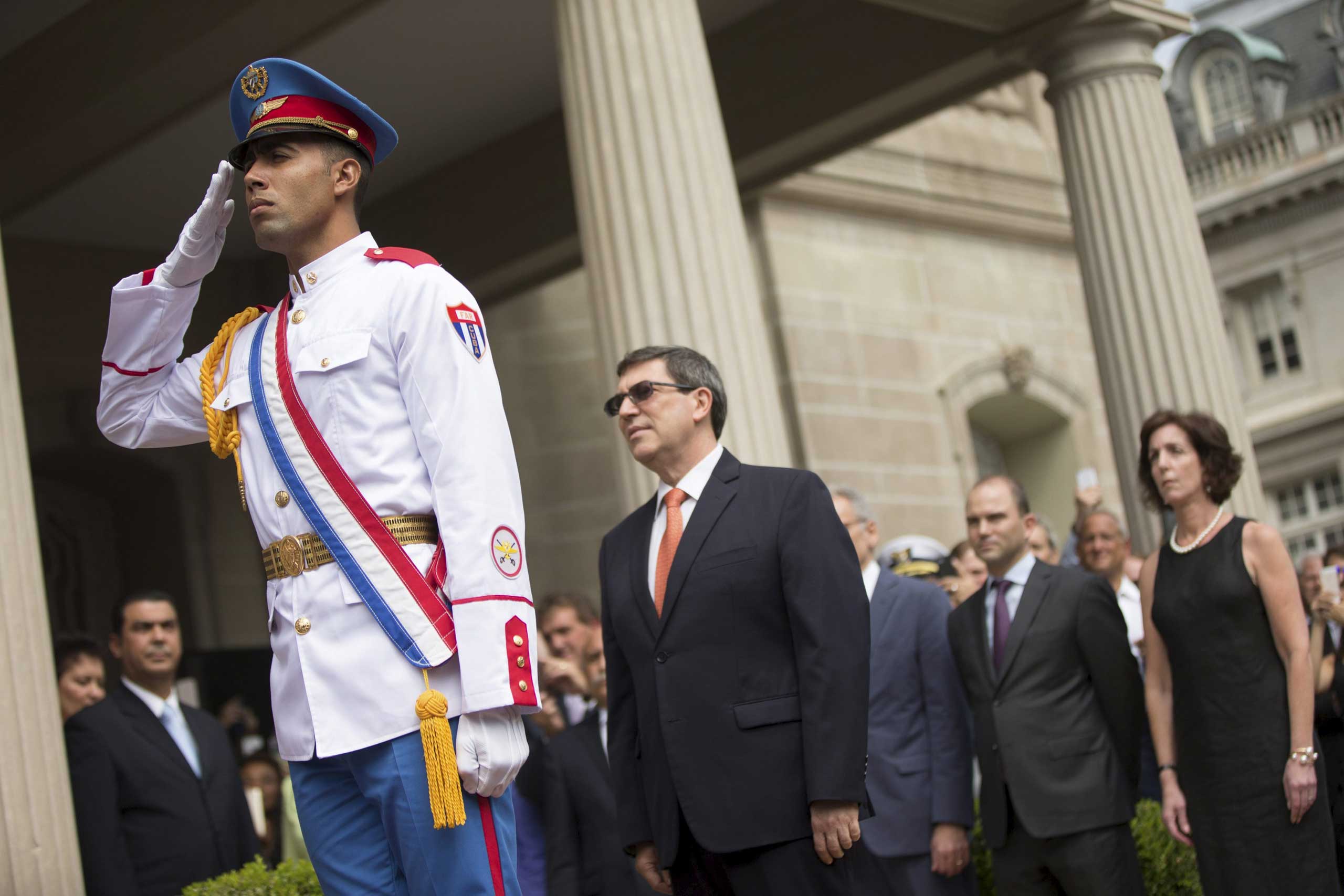 A member of a Cuban honor guard salutes as Cuban Foreign Minister Bruno Rodriguez prepares to raise the Cuban flag over their new embassy in Washington, on July 20, 2015.