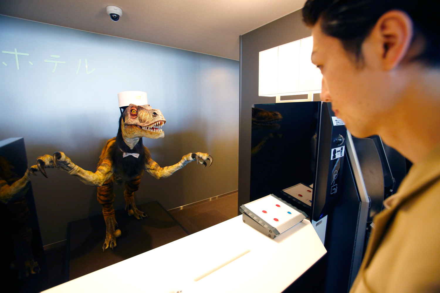 A receptionist dinosaur robot greets a hotel employee demonstrating how to check in for the media at the new hotel, aptly called Henn na Hotel or Weird Hotel, in Sasebo, southwestern Japan, July 15, 2015. (Shizuo Kambayashi—AP)