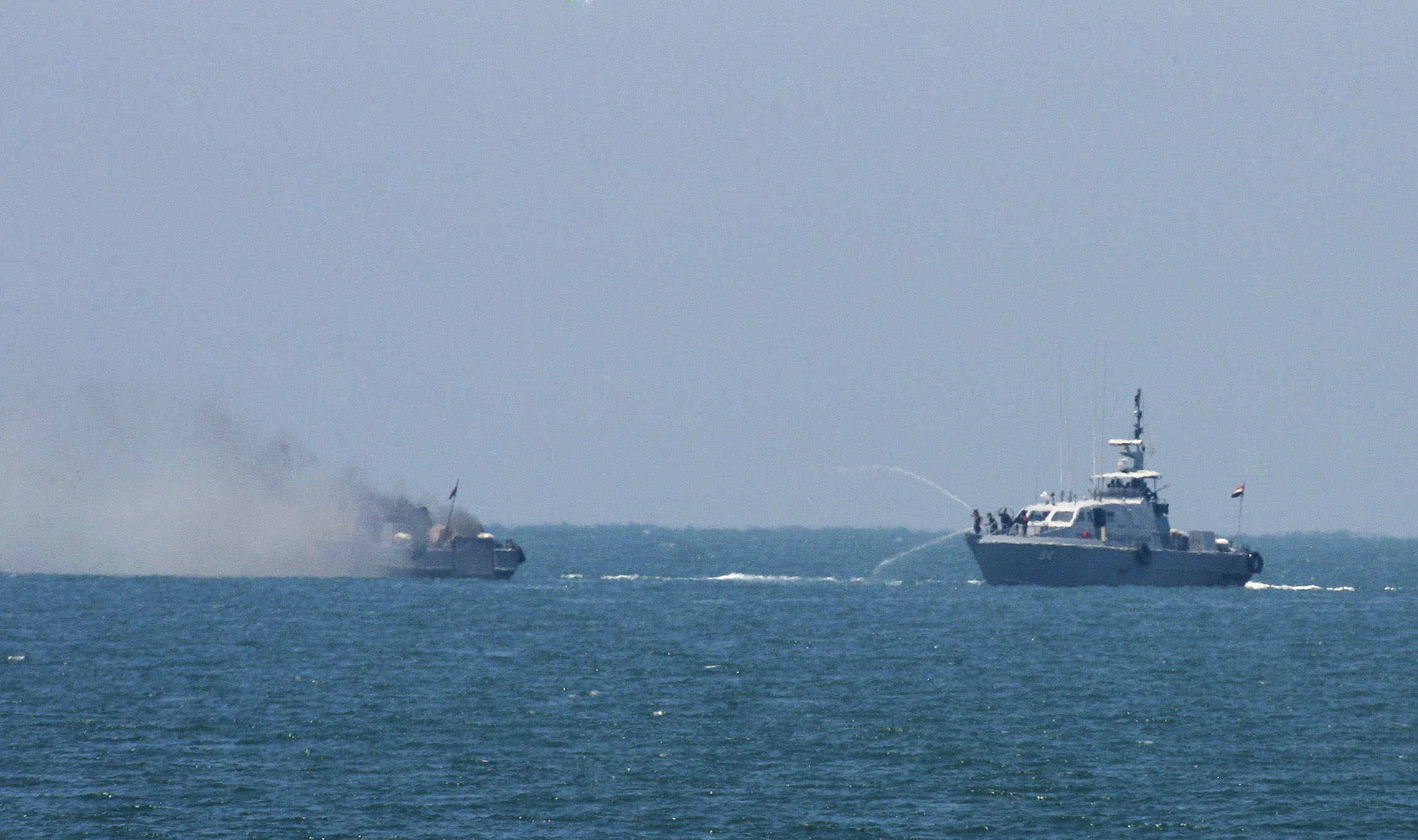 An Egyptian navy vessel hoses down another, which caught fire on the Mediterranean Sea after an exchange of gunshots with militants on July 16, 2015. (Eyad Baba—AP)