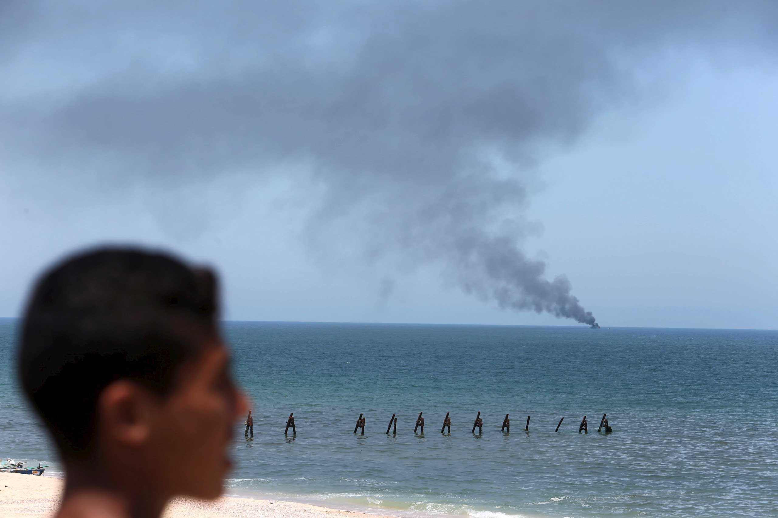 Palestinian watches as smokes rises from an Egyptian coastguard vessel on the coast of northern Sinai, as seen from the border of southern Gaza Strip with Egypt