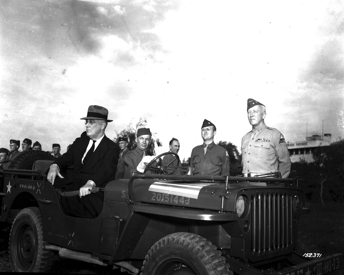 Franklin D. Roosevelt (in suit, seated in jeep at left) reviews US troops as military commander Lieutenant General George S. Patton (right), Casablanca, Morocco, Jan. 17, 1943. (PhotoQuest / Getty Images)