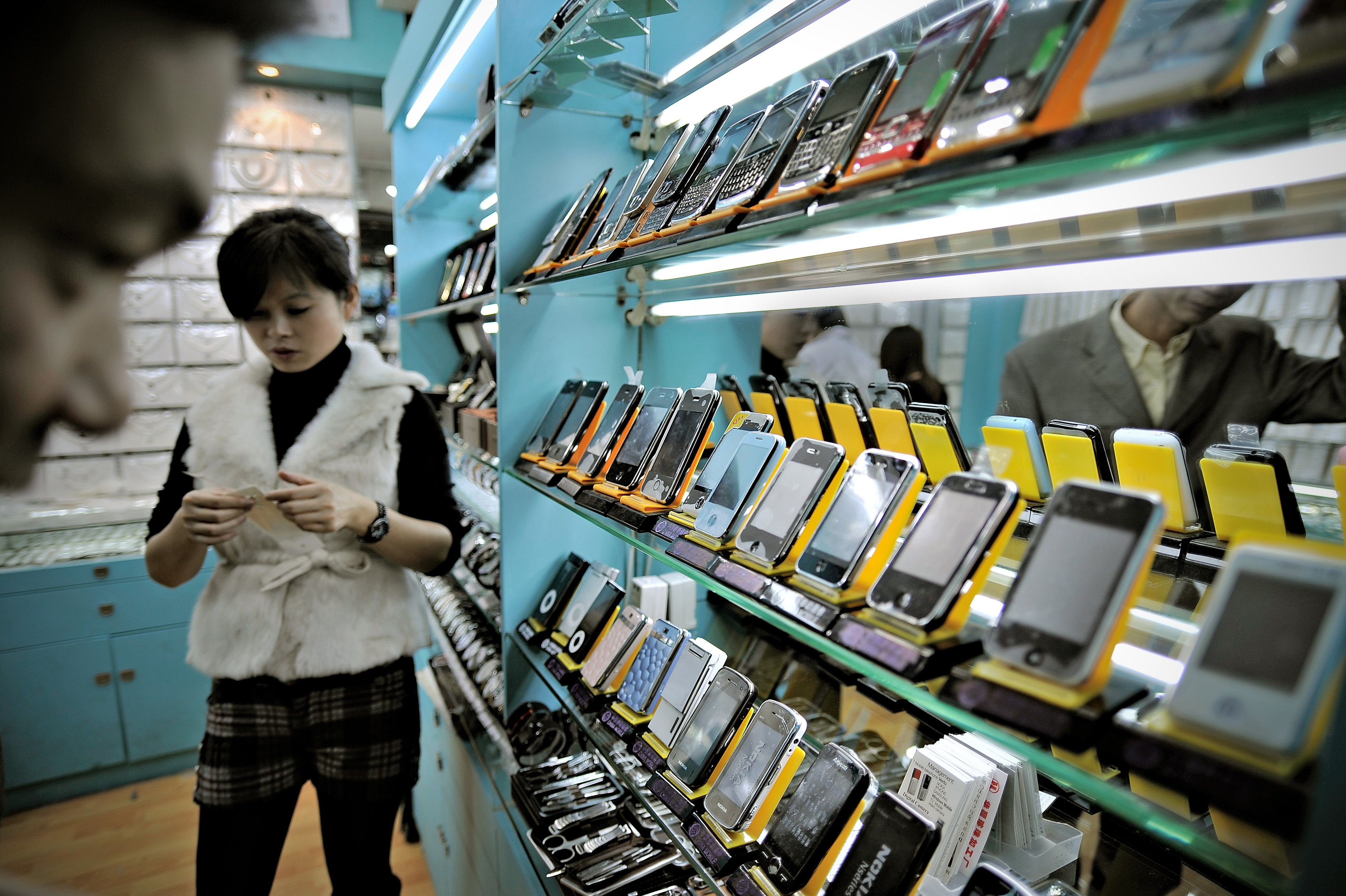 A man looking at fake iPhones displayed in a shop at a market known for counterfeit US goods and housed in the metro station connected to the Science and Technology Museum in Shanghai. (PHILIPPE LOPEZ&mdash;AFP/Getty Images)